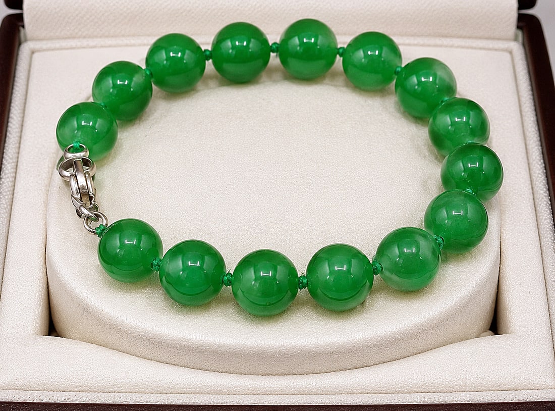Vintage bracelet of 15 spherical beads of natural emerald green jade: Vintage bracelet composed of 15 spherical, calibrated beads of natural emerald green jade, 12 mm in diameter. Beads strung with individual knots and a silver clasp. Length: 23 cm. Weight: 38 g.