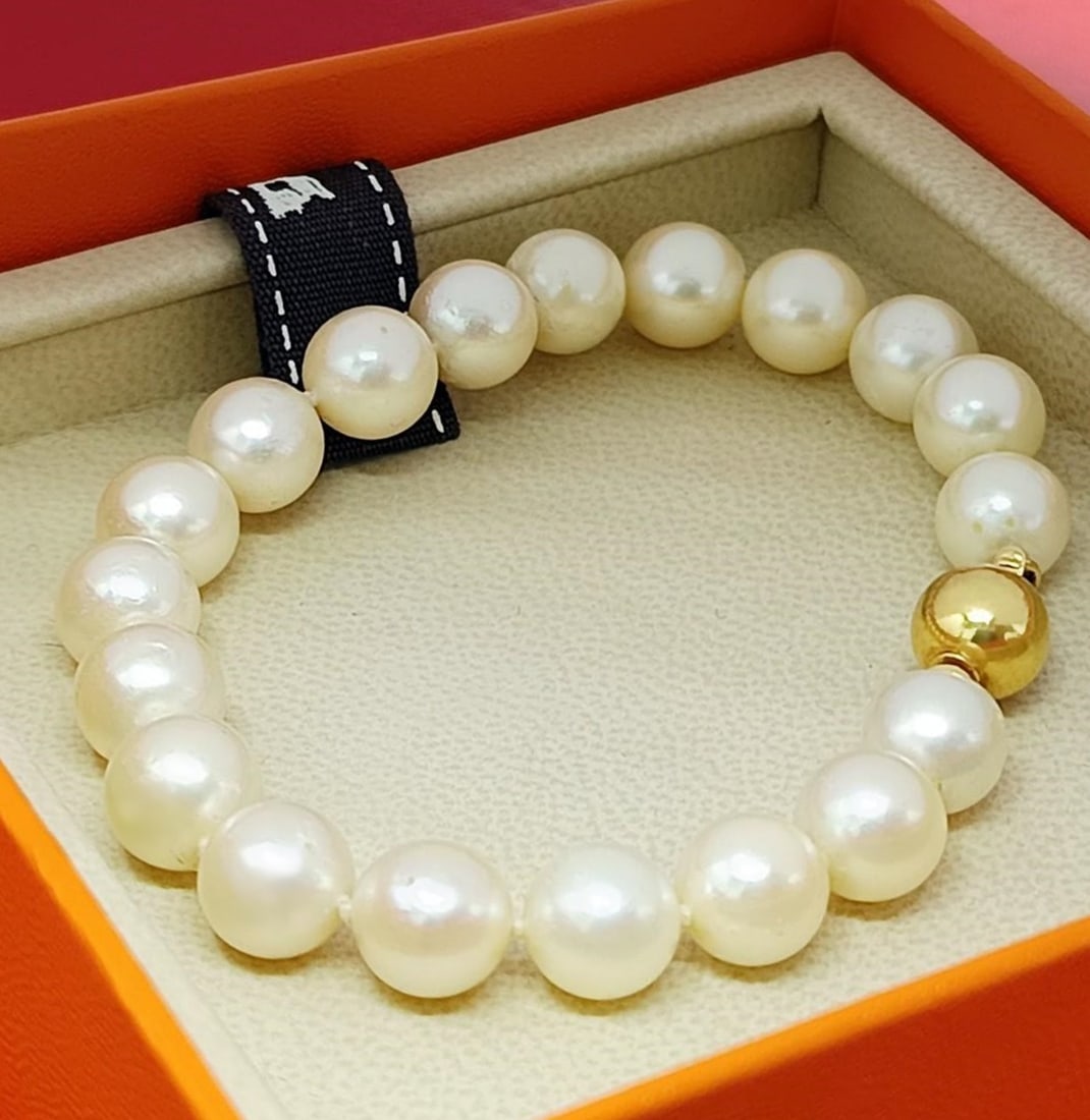 Vintage bracelet of 19 white cultured pearls with an 18-karat gold clasp: Vintage bracelet composed of 19 individually knotted, spherical, white cultured pearls, 9 mm in diameter. Large spherical clasp with safety lock, crafted from 18k gold. Hallmarked. Length: 20 cm. Weig