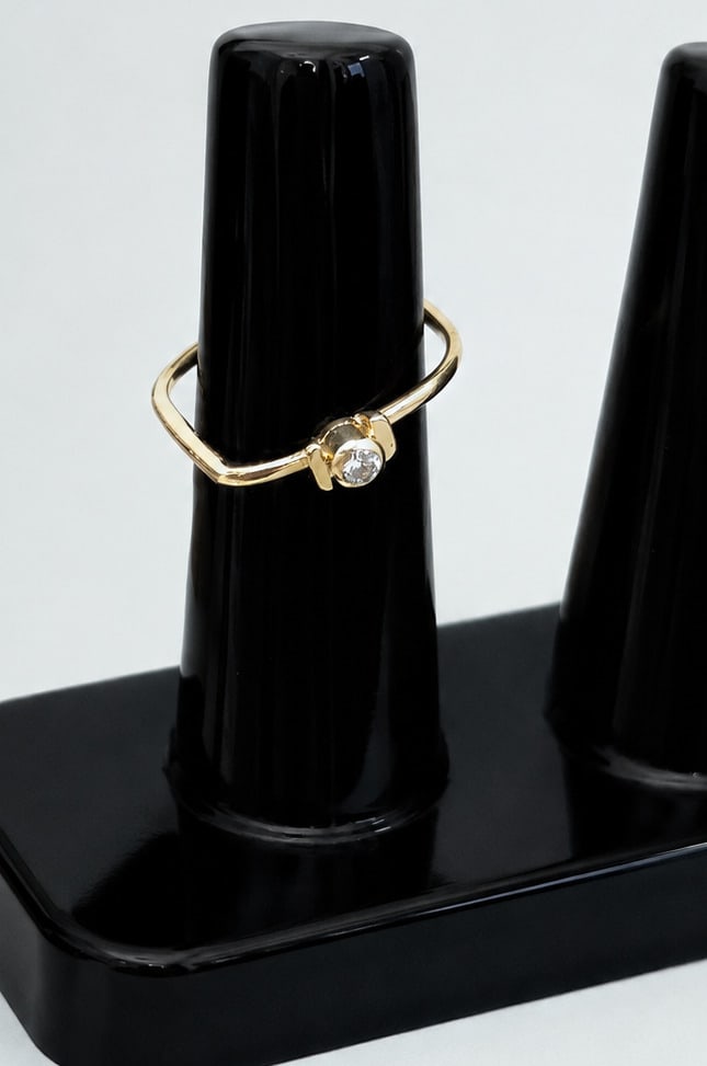Minimalist 18-karat yellow gold solitaire ring with diamond: Modern and minimalist design ring crafted in 18k yellow gold, featuring a curved band and a 0.06 ct brilliant-cut diamond set in a bezel setting. Hallmarked and stamped on the band. Tatum size: No. 12