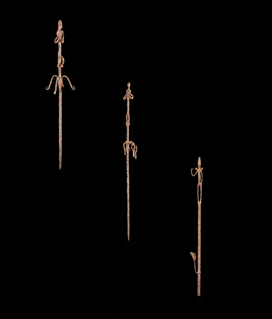 Three staffs of dignity topped with human figures, Bamana, Mali, 19th-20th centuries: A set of wrought iron, comprising three stylized, vertically oriented ritual or ceremonial staffs, each topped with small, stylized human figures and various curved and geometric elements crafted thro