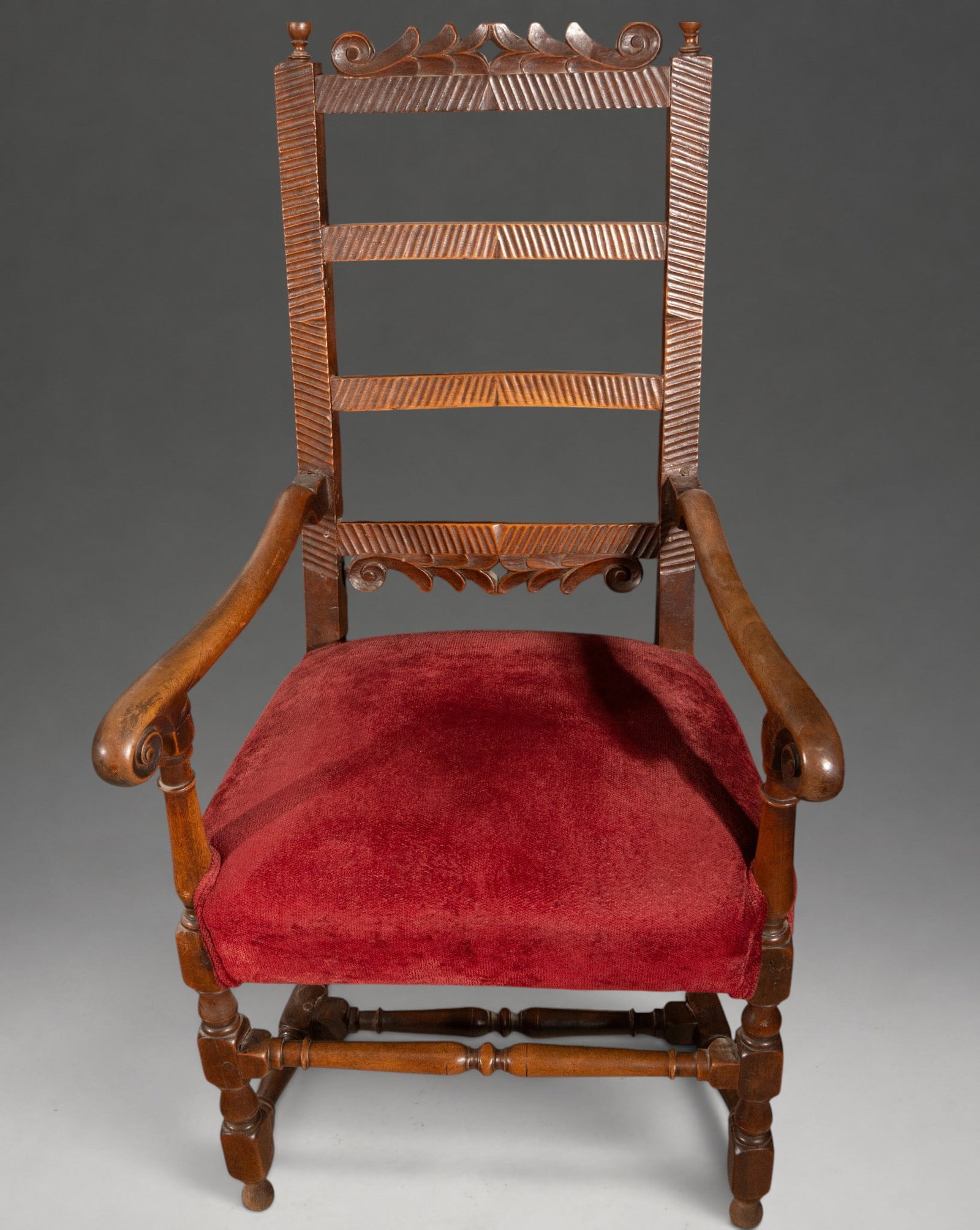 Carved wooden armchair with openwork back – 17th century: Carved wooden armchair. Dimensions: 122 × 64 × 59 cm. High, open backrest, articulated by means of crossbars decorated with diagonal fluting and a carved vegetal finial. Curved arms ending in a scro