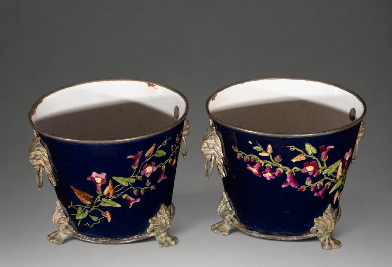 Pair of French jardinières with bronze mounts – France, Empire style – 19th century: Pair of porcelain vases or cachepots glazed in cobalt blue, decorated with polychrome flowering branches in relief. Bronze metal mounts with lateral masks fitted with movable rings and supports in the