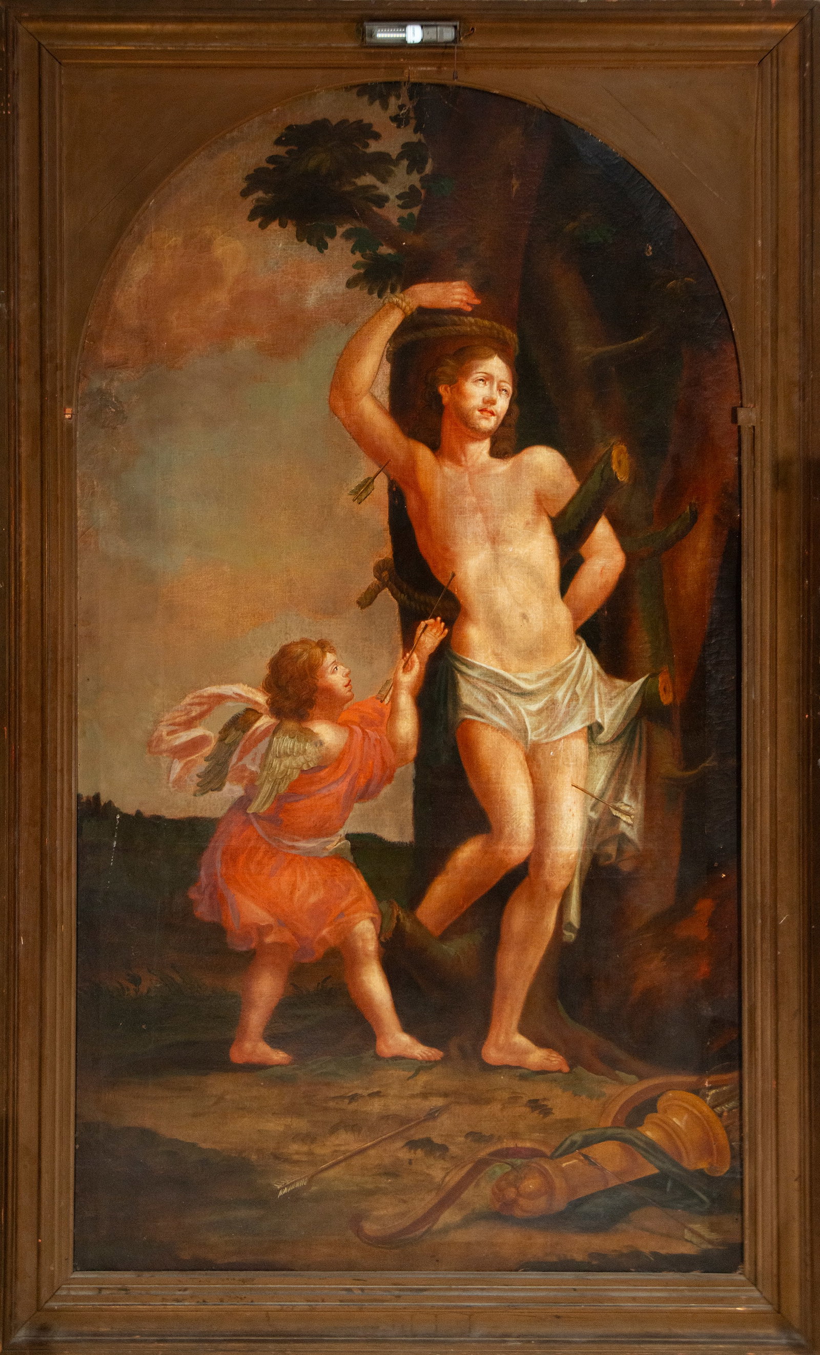 Martyrdom of Saint Sebastian – European Master – 18th Century: Oil on canvas. Dimensions of the work: 215 × 127 cm; with frame: 253 × 157 cm. Depiction of the martyrdom of Saint Sebastian, tied to a tree and pierced by arrows, accompanied by an angel who interv