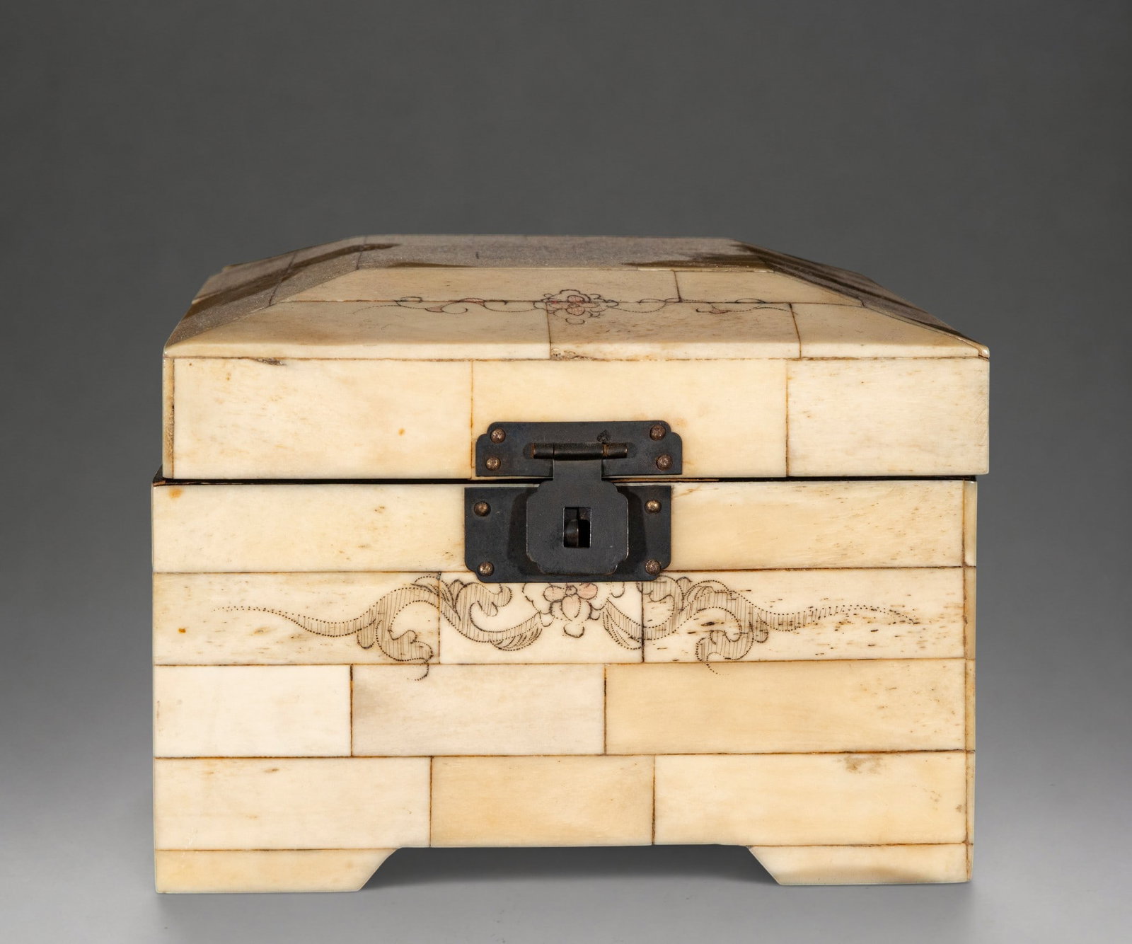 Box lined with bone plates with incised decoration – 20th century: Rectangular wooden box covered externally with bone plates arranged in an irregular checkerboard pattern. The lid is slightly domed and hinged with a metal hinge; the front has an iron clasp. It featu