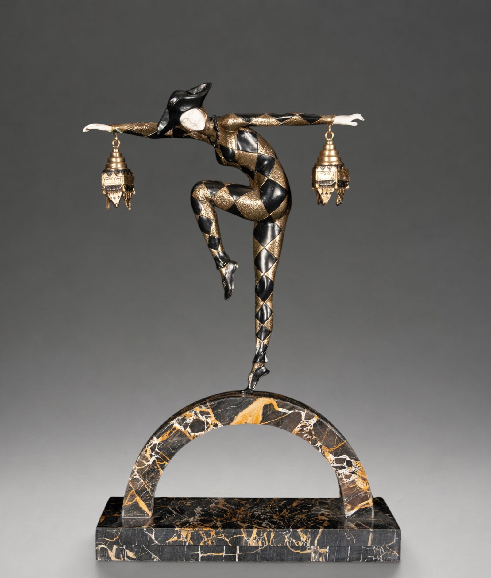 Important 20th Century Chryselephantine - According to Marcel-André Bouraine, Signed: Chryselephantine sculpture in the Art Deco style depicting a harlequin in an acrobatic pose, dressed in a black and gold rhomboid costume and holding two hanging lanterns with outstretched arms. Face 