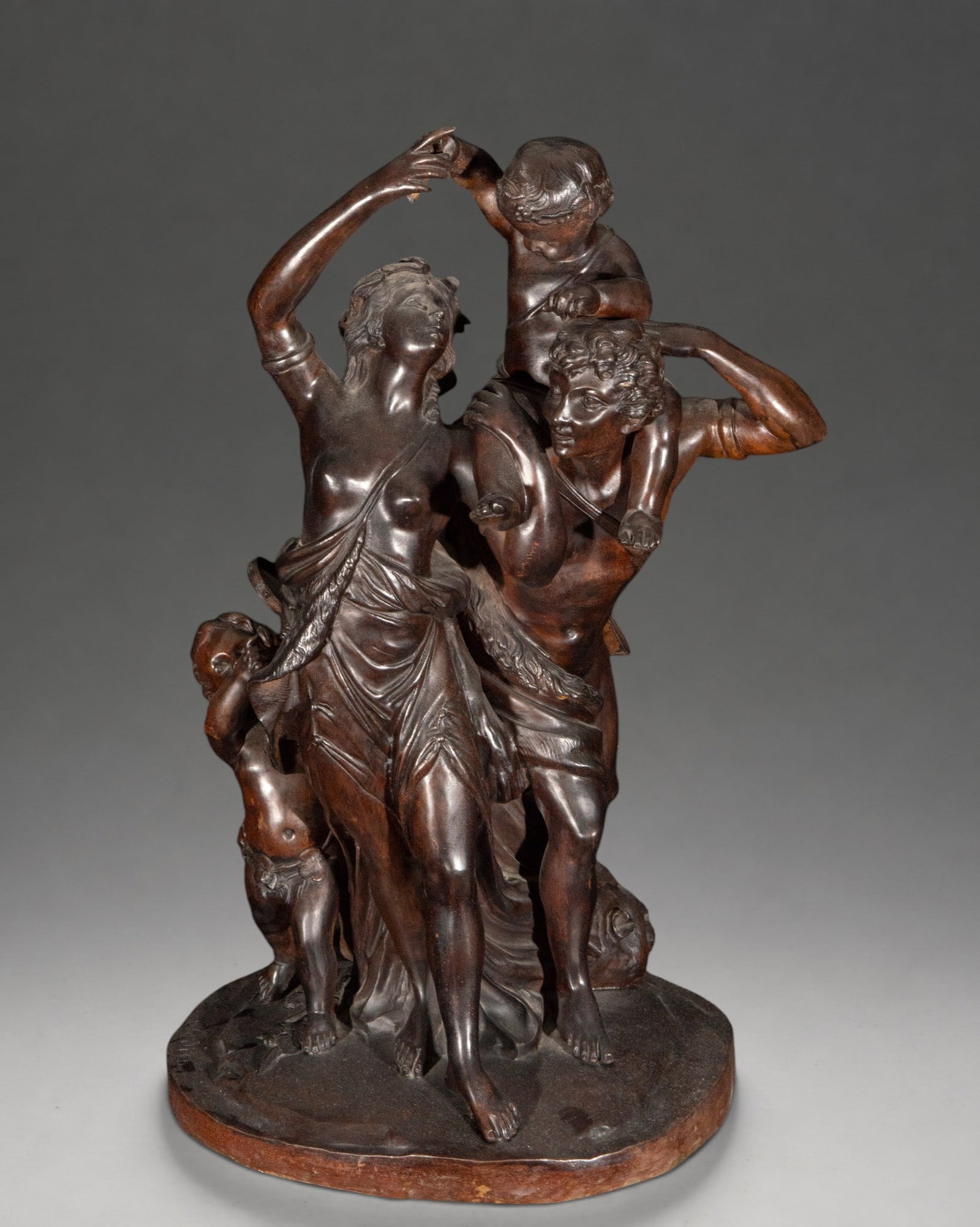 Bacchic group with couple and cherubs, signed “Clodion?? – 19th century: A patinated bronze sculpture group, inspired by Neoclassical and Rococo styles, depicting a semi-nude couple accompanied by cherubs in a dynamic, Bacchanalian composition. The figures' arms and gestur