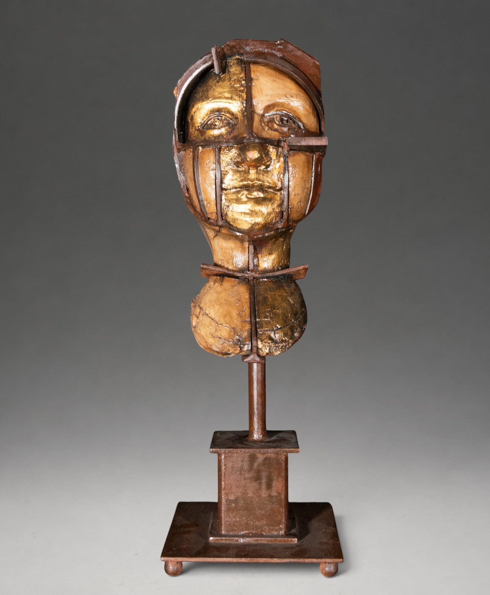 Desert Woman, signed “F. Seguí?? – Spanish School – late 20th-early 21st century: Contemporary sculpture of a female bust constructed from a combination of wood and iron. The face, modeled in different tones and partially gilded, is divided by metal bands that run vertically and ho