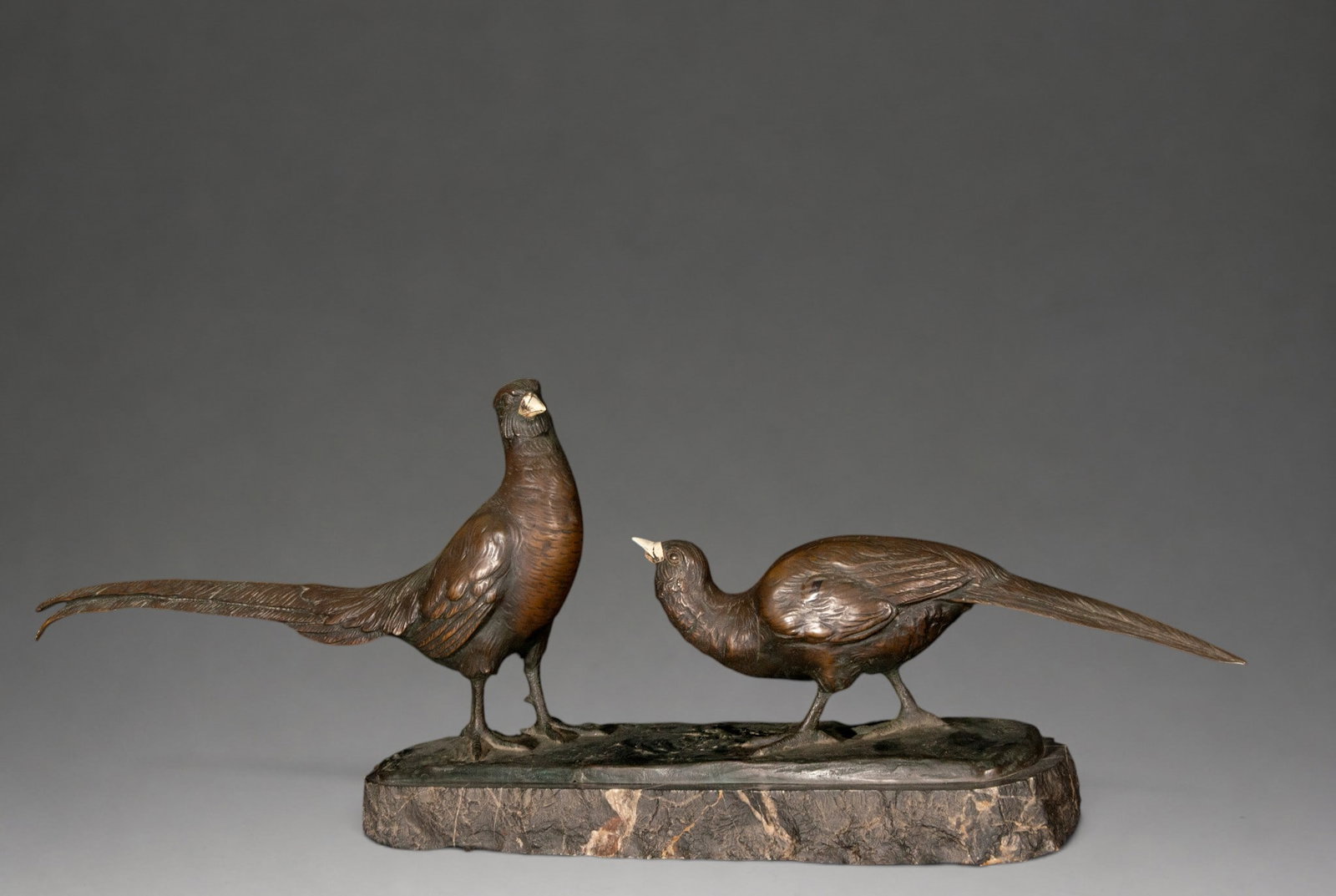 Pair of pheasants, Peder Marius Jensen, signed - Danish School - ca. 1910: A patinated bronze sculpture group depicting a pair of pheasants on a naturalistic background, a male standing upright and a female leaning towards him, both with long tails extended. The beaks are ma