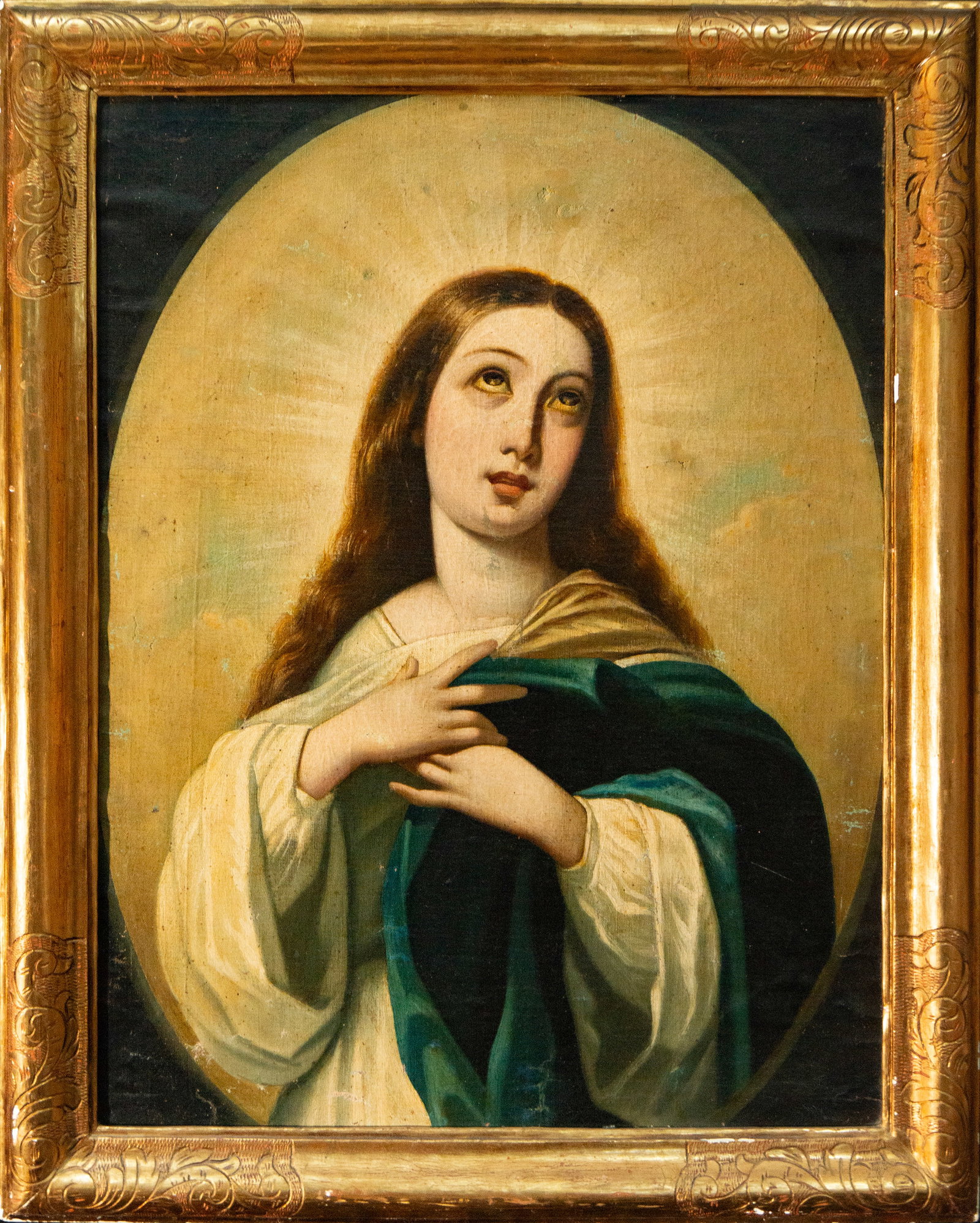 Virgin in prayer – Spanish School – 19th century: Oil on canvas. Half-length portrait of the Virgin Mary, with her hands crossed over her chest and her gaze raised, dressed in a light tunic and a blue-green mantle. The figure is set within a luminous
