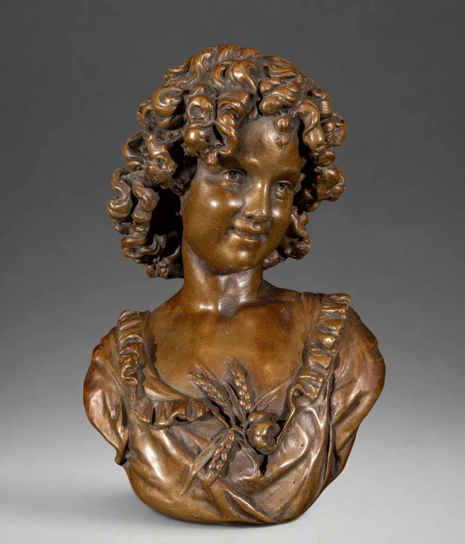 Allegory of the Harvest or Ceres - 19th century bronze bust, France: Patinated, cast, and chiseled bronze. Decorative female bust depicting abundant curly hair and a square-necked dress adorned with ruffles. On her chest, she holds a small sheaf of wheat and vegetal mo