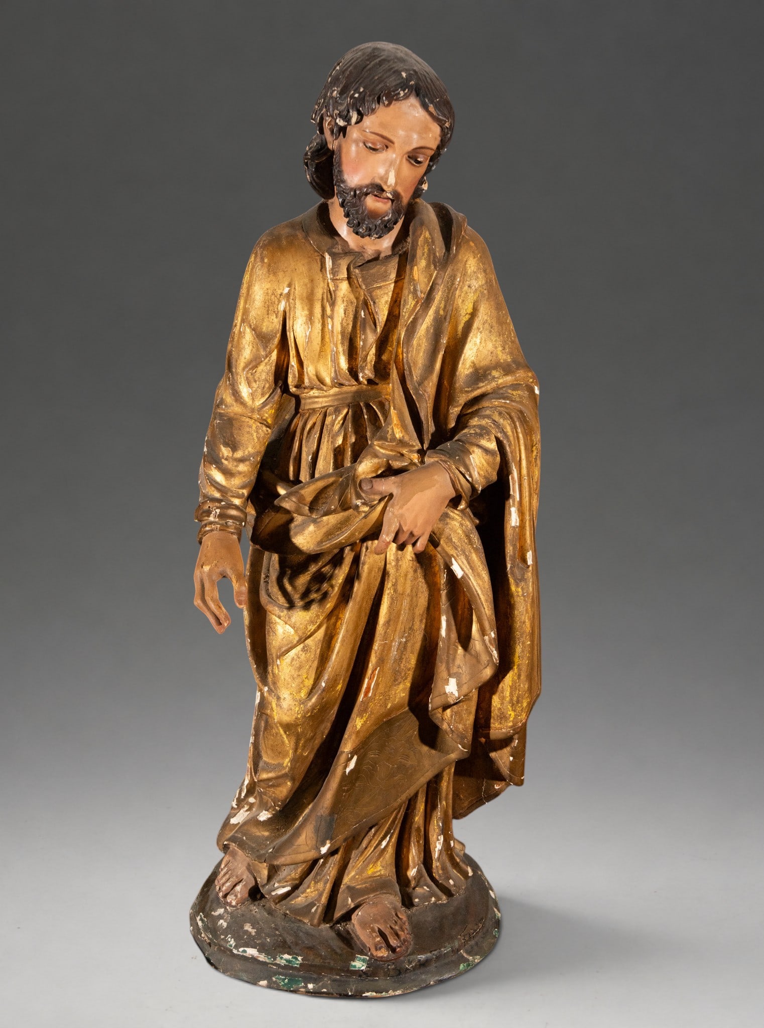 Large Wooden Carving of Saint Joseph - Italian School of the 18th Century: Requires minor restoration. A freestanding sculpture in the round, carved, polychromed, and gilded wood, depicting Saint Joseph. The figure stands with his head bowed and gaze lowered, dressed in a cl