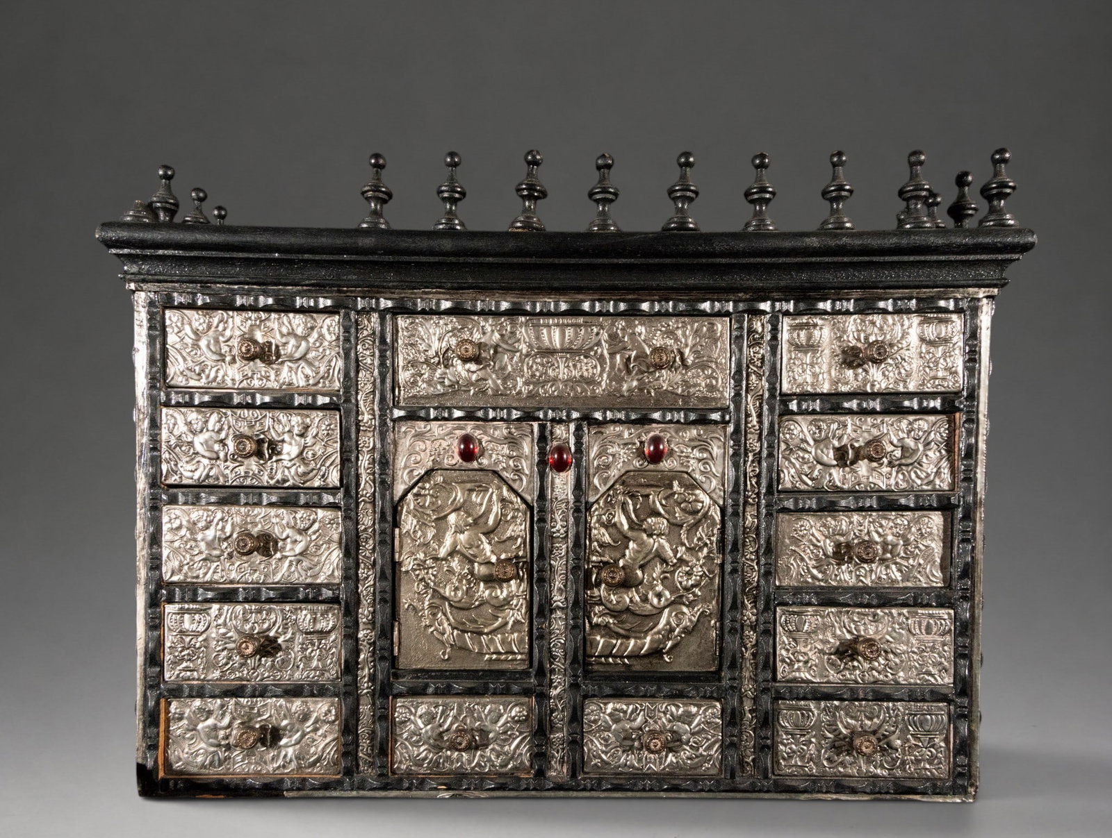 Beautiful colonial tabletop cabinet, 18th-19th century: A miniature bargueño or cabinet with an architectural structure, featuring a front organized with multiple drawers and a central compartment with two doors. It is decorated with embossed metal plates