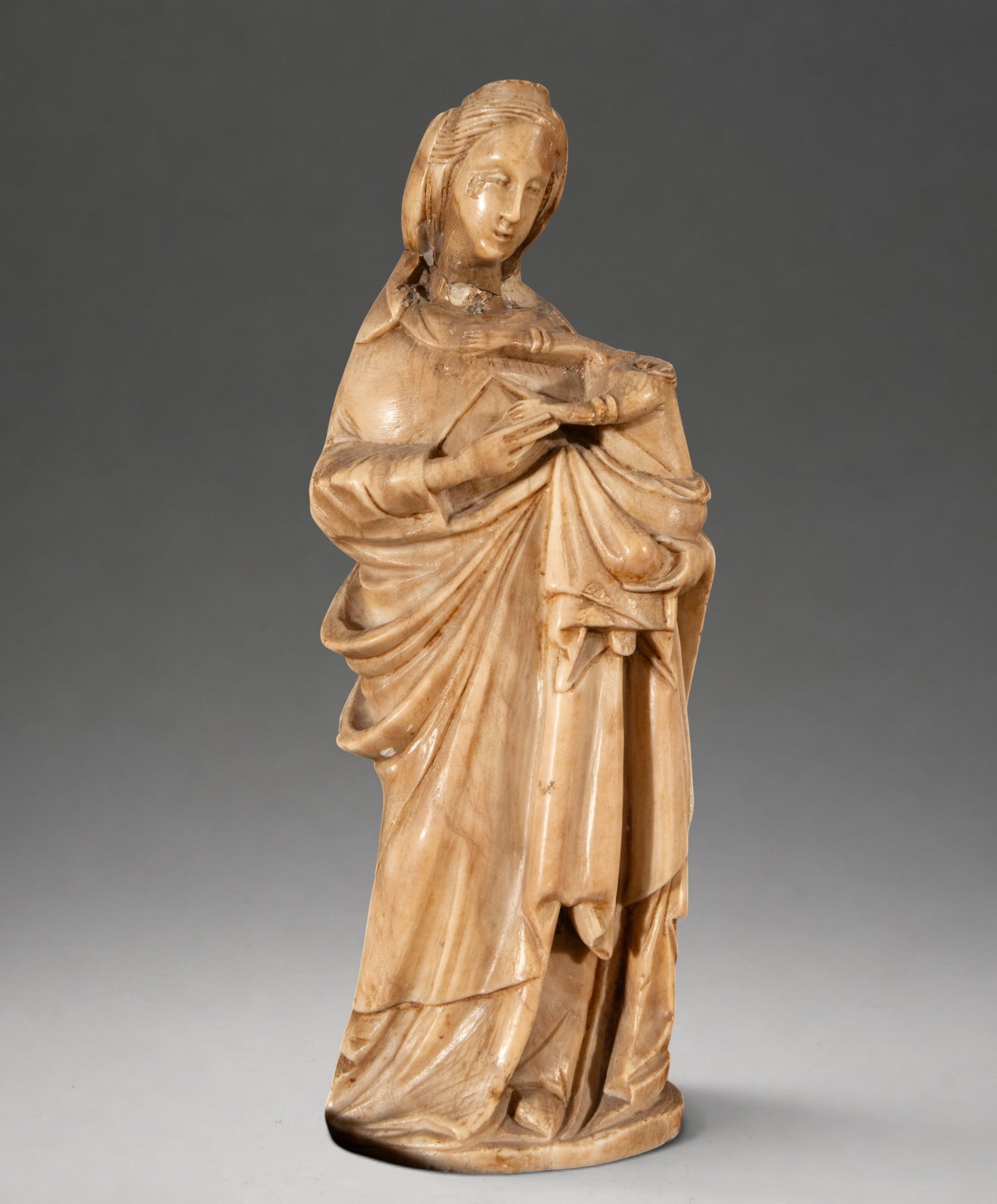 Madonna in alabaster according to Gothic models – Southern Italian School: A sculpture in the round, carved from alabaster, depicting the Virgin Mary standing with the Christ Child in her arms. The composition follows Gothic devotional models from southern Italy, with a fron