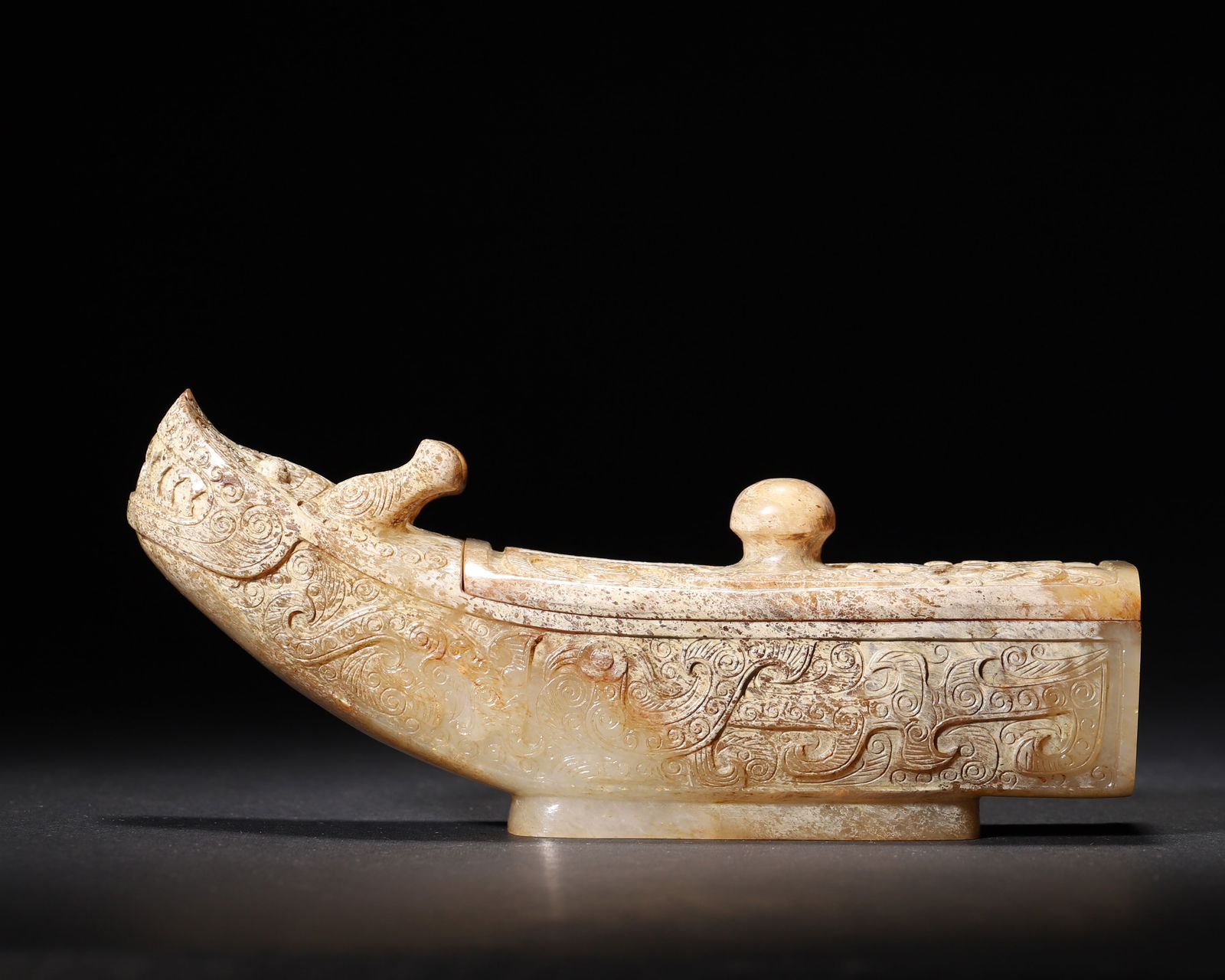 Han dynasty archaic jade patinated dragon-head boat-form lidded box: Han dynasty archaic jade boat-form lidded box, made of patinated jade. Adorned with dragon-head and cloud reliefs, its delicate boat shape makes it a fine example of han jade art, embodying ancient ri