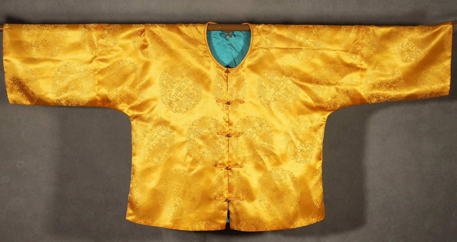 Qing dynasty, imperial yellow satin informal robe with hidden dragon medallions: A Qing imperial informal robe made of imperial yellow satin, intricately woven with hidden dragon medallions. The exquisite craftsmanship and luxurious color scheme, paired with a turquoise lining, re