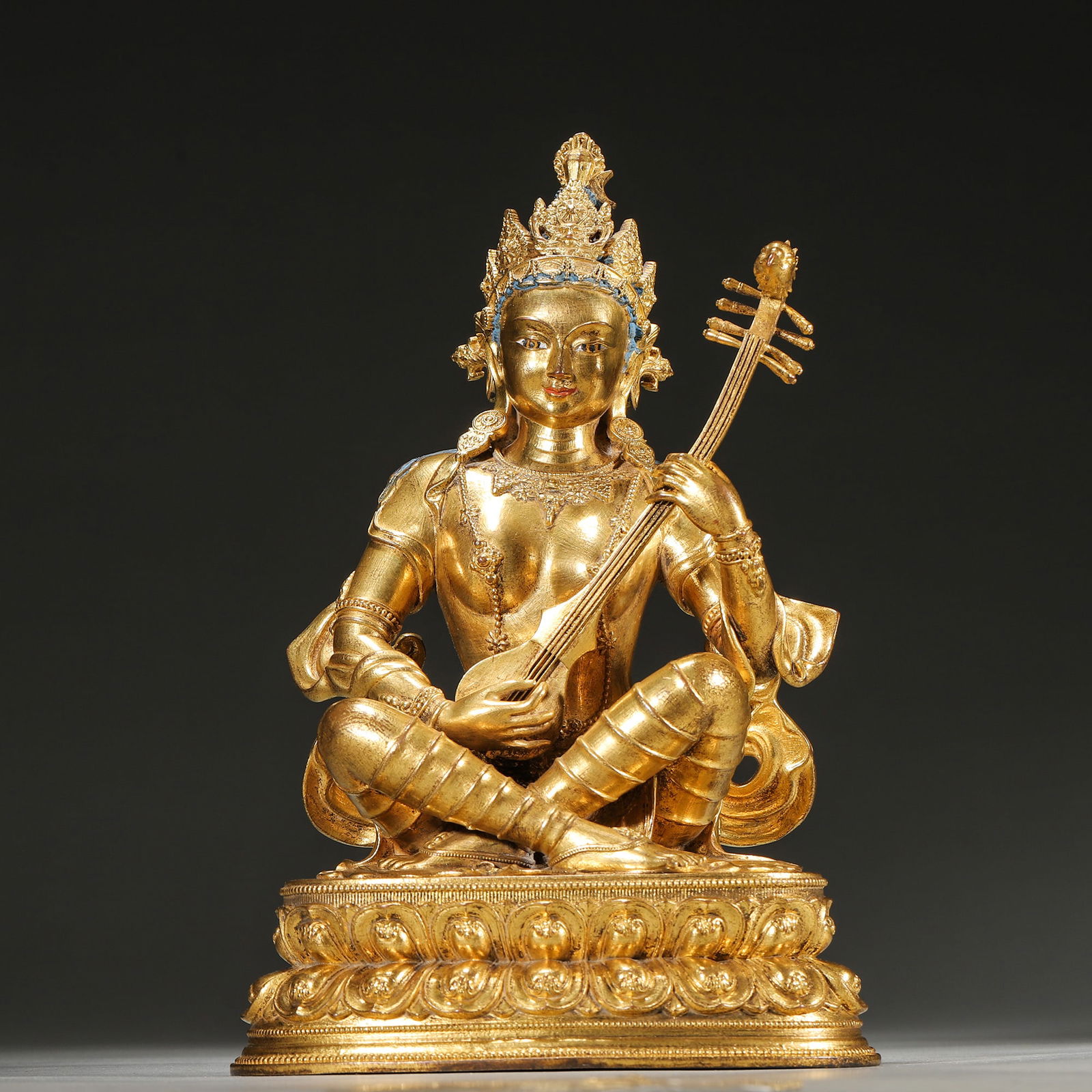 Mid-qing dynasty, gilt bronze statue of saraswati (goddess of music): Made by the qing court workshop during the qianlong period, this gilt bronze statue depicts saraswati seated in a relaxed pose, holding a pipa. The base is sealed and engraved with a vajra motif,