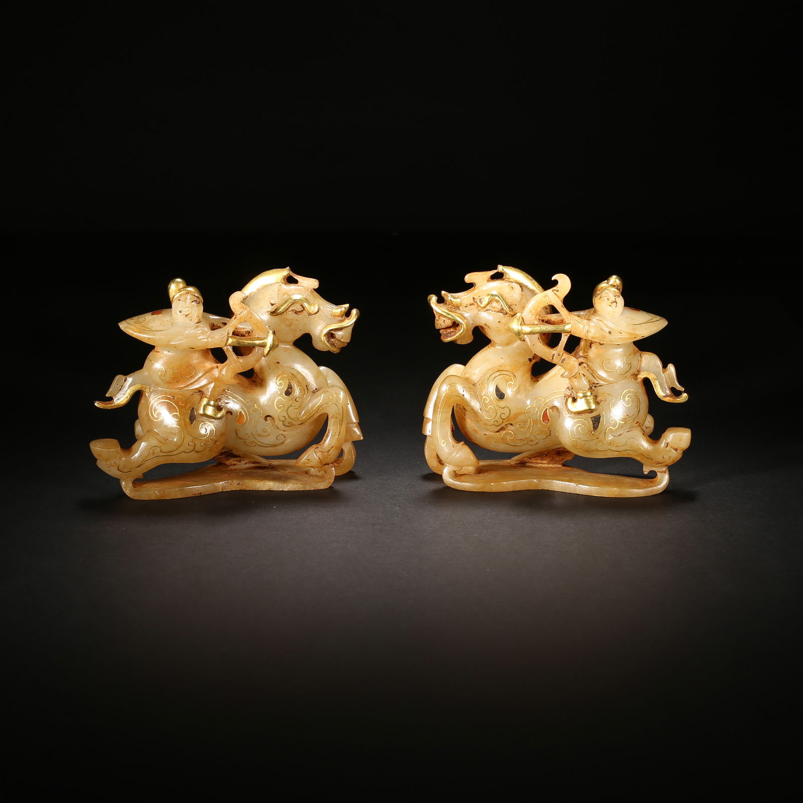 Han dynasty, a pair of white hetian jade ornaments with gold inlay: immortal riding a heavenly horse: This pair of white hetian jade ornaments from the han dynasty features round-carved immortals riding heavenly horses, decorated with gold-inlaid cloud patterns. With exquisite craftsmanship and