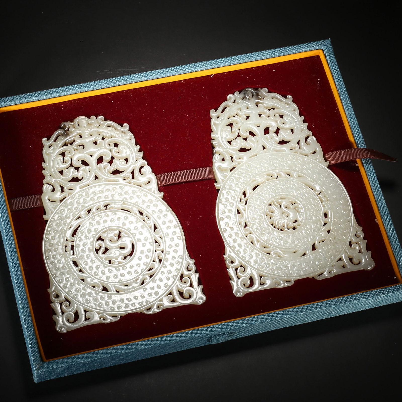 Warring states to han dynasty, a pair of white hetian jade bi with openwork dragon-phoenix patterns: This pair of white hetian jade bi from the warring states to han dynasty features an ingenious triple-ring nested design, with openwork dragon-phoenix patterns on the protruding rim and grain