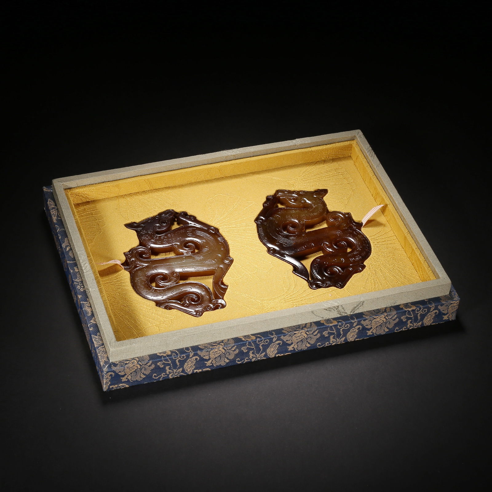 Han dynasty, a pair of yellow hetian jade pendants with openwork chi-dragon patterns and black: This pair of yellow hetian jade pendants from the han dynasty features dynamic s-shaped openwork chi-dragons with cloud motifs incised on their bodies, and rich natural black patina. As core component