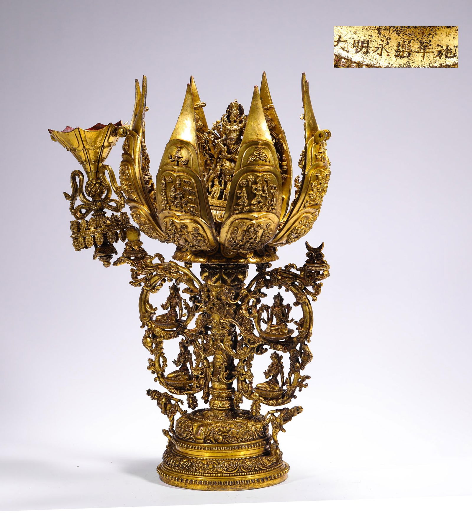 A GILDED BRONZE LOTUS BUDDHA STATUE FROM YONGLE IN THE MING DYNASTY: H:55cmW:26cmWeight:10780g The entire piece is gilded, featuring a fully bloomed lotus as its main design. The petals and base are adorned with intricate Buddhist statues and guardian motifs, showcasin