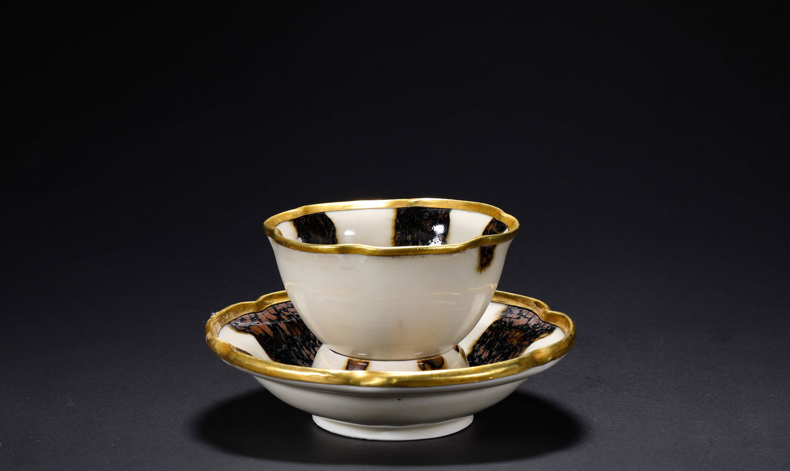 IN THE SONG DYNASTY, DING KILN GILDED COPPER TEA BOWL WITH A WRAPPED MOUTH: H:6.5cmD11.5cm The white glazed, spotted and gold-mouthed flower-mouthed saucer of Ding Kiln in the style of the Song Dynasty was a tea-drinking vessel for the ancient noble class.