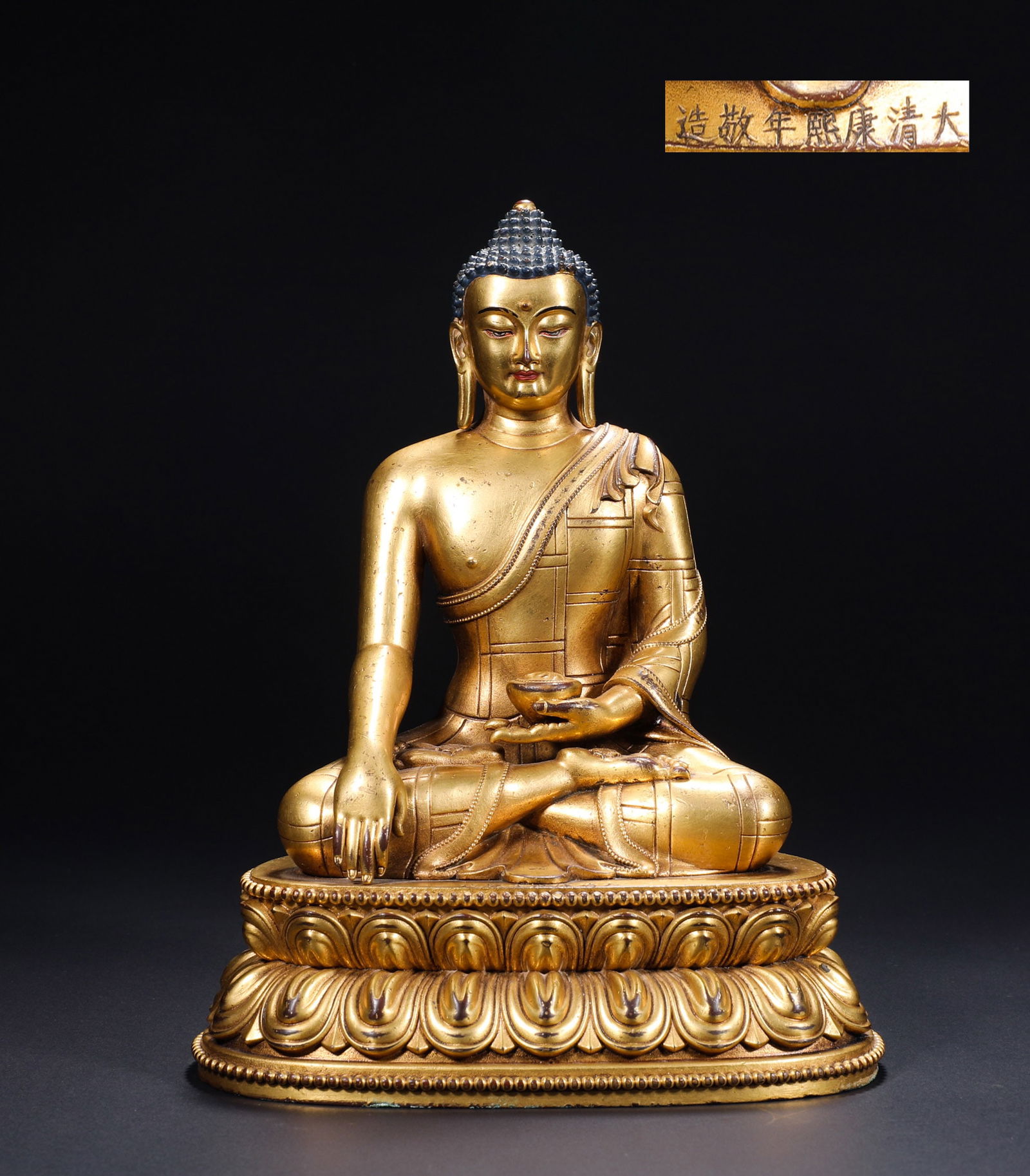 A BRONZE GILDED BUDDHA STATUE OF EMPEROR KANGXI IN THE QING DYNASTY: H:21cmW:15.8cmWeight:1510g This is a gilded bronze seated statue of Sakyamuni Buddha from the Kangxi period of the Qing Dynasty, an exquisite imperial Tibetan Buddhist sculpture made by the Qing