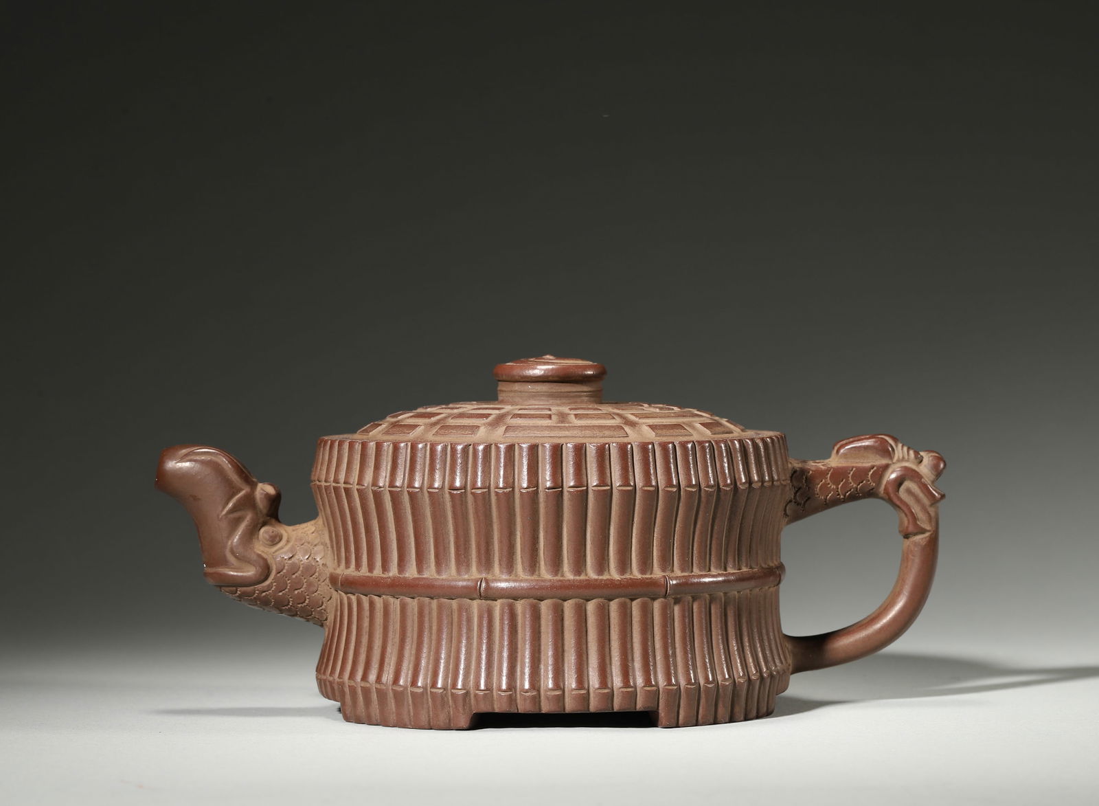 A FINE QING DYNASTY (19TH CENTURY) ZISHA TEAPOT WITH BAMBOO BUNDLE FORM AND DRAGON-HEADS, DECORATED: 7.87" x 3.94" x 3.35" inches (20.0 cm x 10.0 cm x 8.5 cm)Crafted in the 19th century, this teapot features a robust Zisha body shaped like a bundle of bamboo, with dragon-head spout and handle. The li