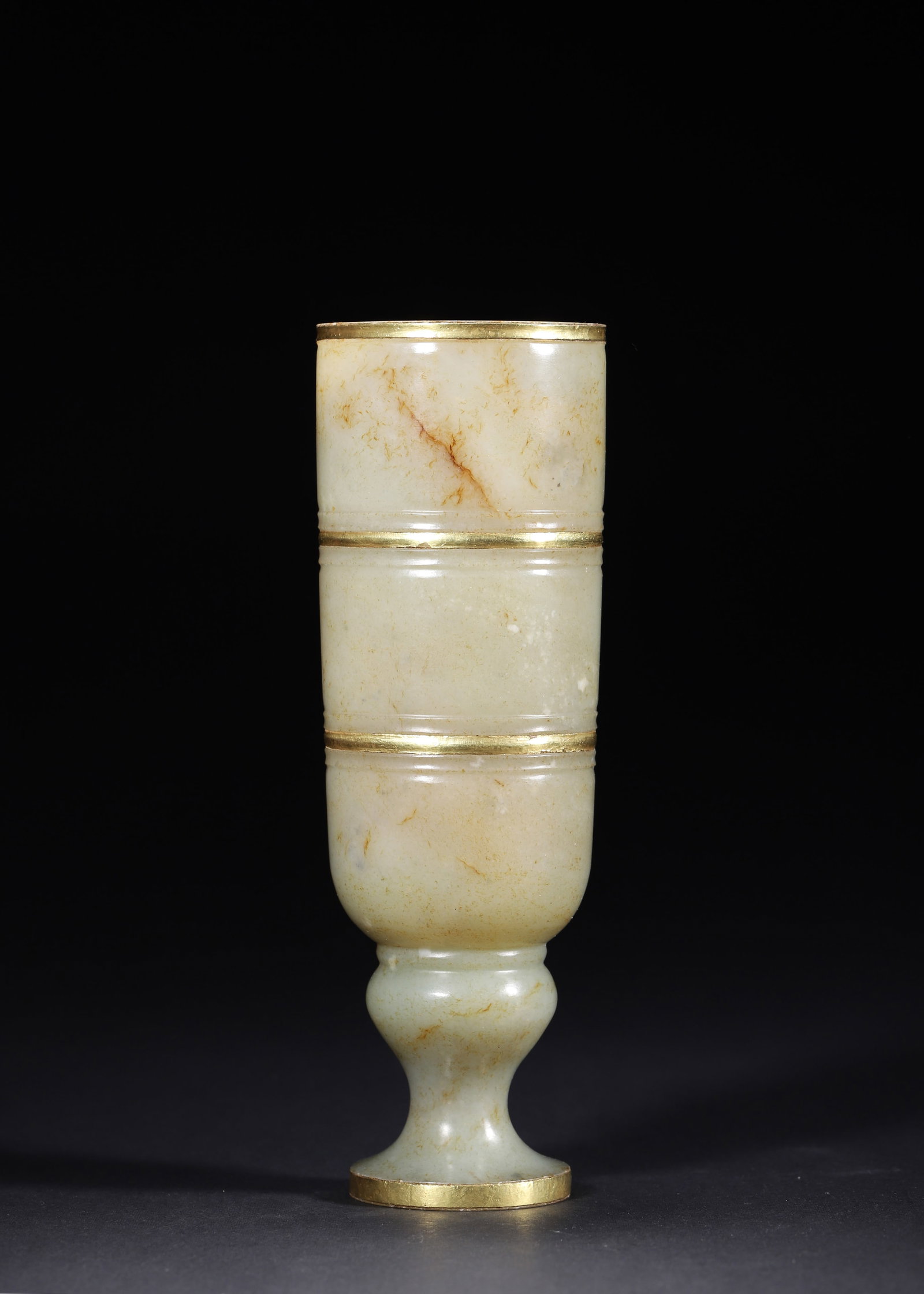 HAN DYNASTY, A GILT-MOUNTED HETIAN JADE STEM CUP: 2.2" x 6.69" inches (5.6 cm x 17.0 cm) | Weight: 0.74 lbs (336.0 g)Carved from Hetian greenish white jade with natural earth patina and gilt mounting, it is a classic royal ritual wine cup of Han Dyna