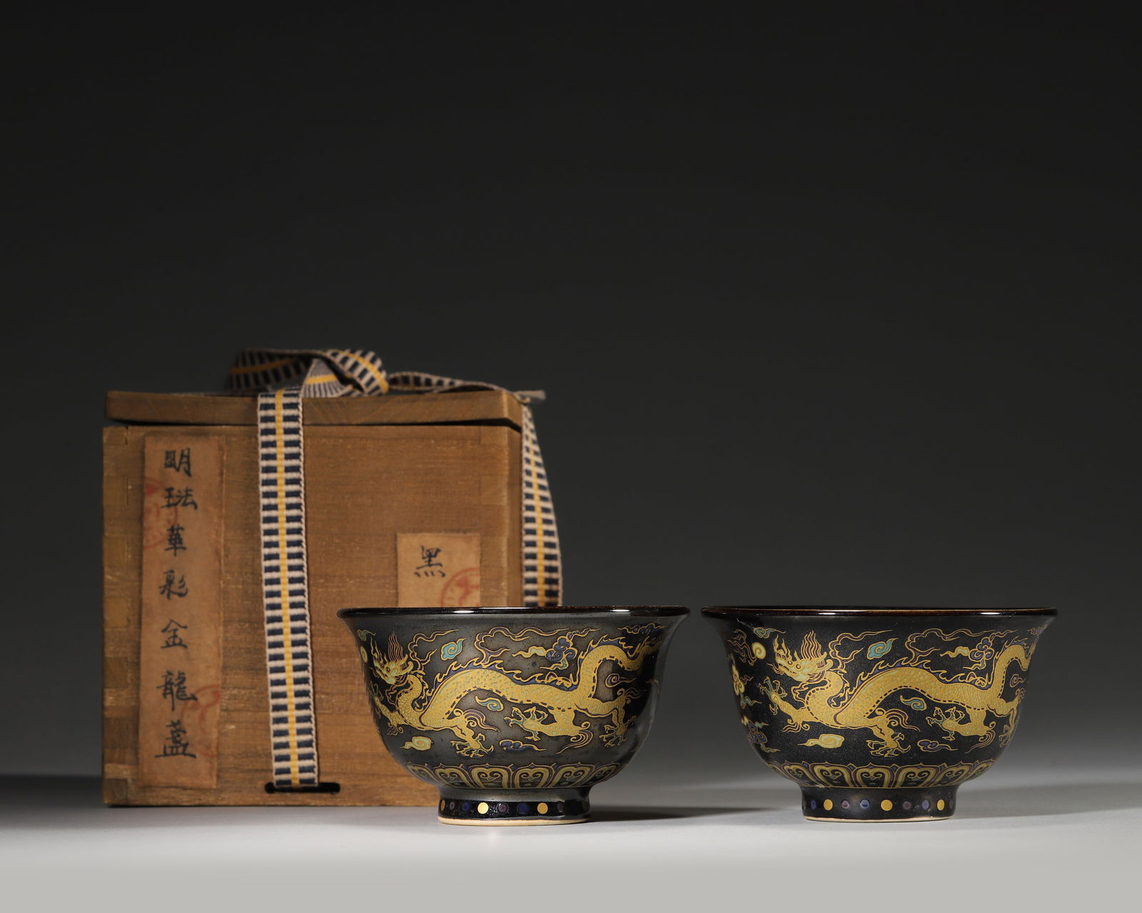 MING DYNASTY XUANDE PERIOD FAHUA-ENAMELED AND GILT 'DRAGON AND CLOUD' BOWLS (A PAIR): 3.54" x 2.17" inches (9.0 cm x 5.5 cm)A magnificent pair of official kiln bowls from the Xuande period, featuring a glossy black glaze adorned with vibrant Fahua enamel and gilded dragon-and-cloud mot
