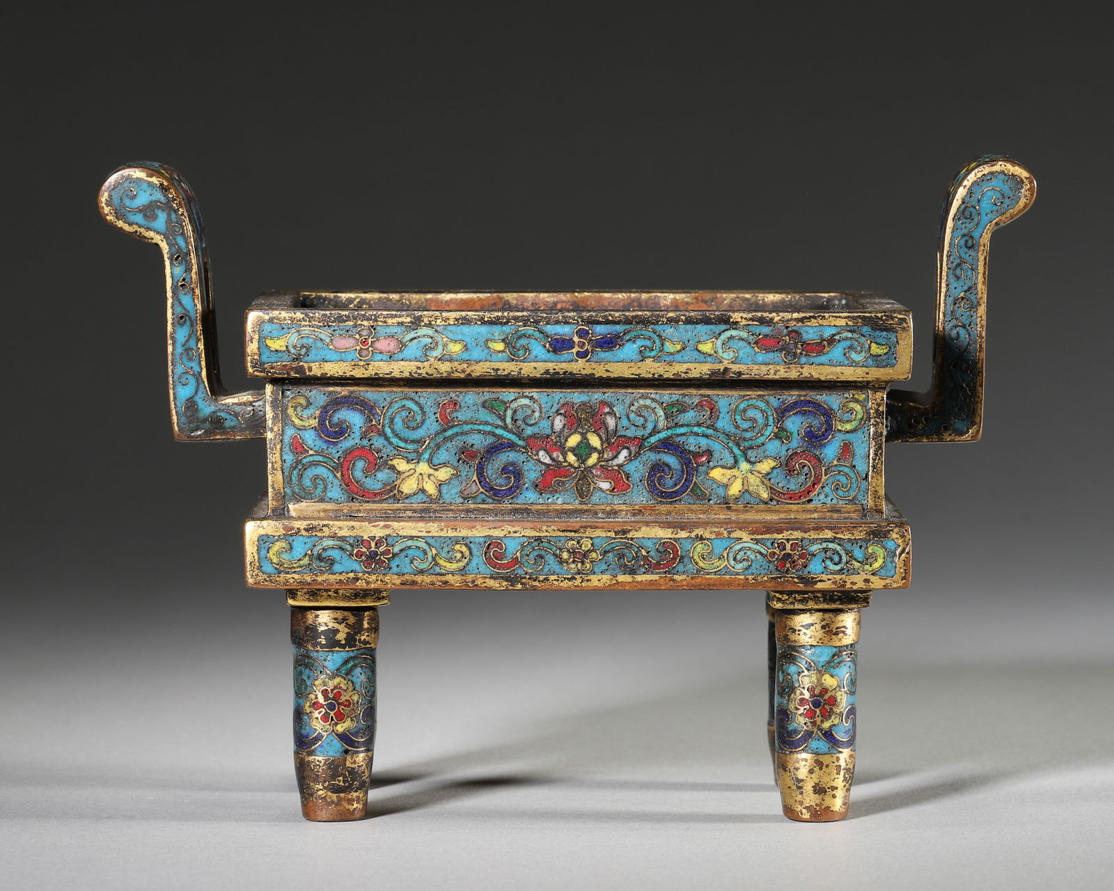 A FINE IMPERIAL GILT-BRONZE CLOISONNÉ ENAMEL 'FLORAL' TRIPOD CENSER, QIANLONG MARK AND PERIOD: 5.51" x 2.36" x 3.94" (14cm x 6cm x 10cm) | 1.44 lbs (653g)A fine imperial gilt-bronze cloisonné enamel 'floral' tripod censer, Qianlong mark and period, of rectangular form with upright handles, of
