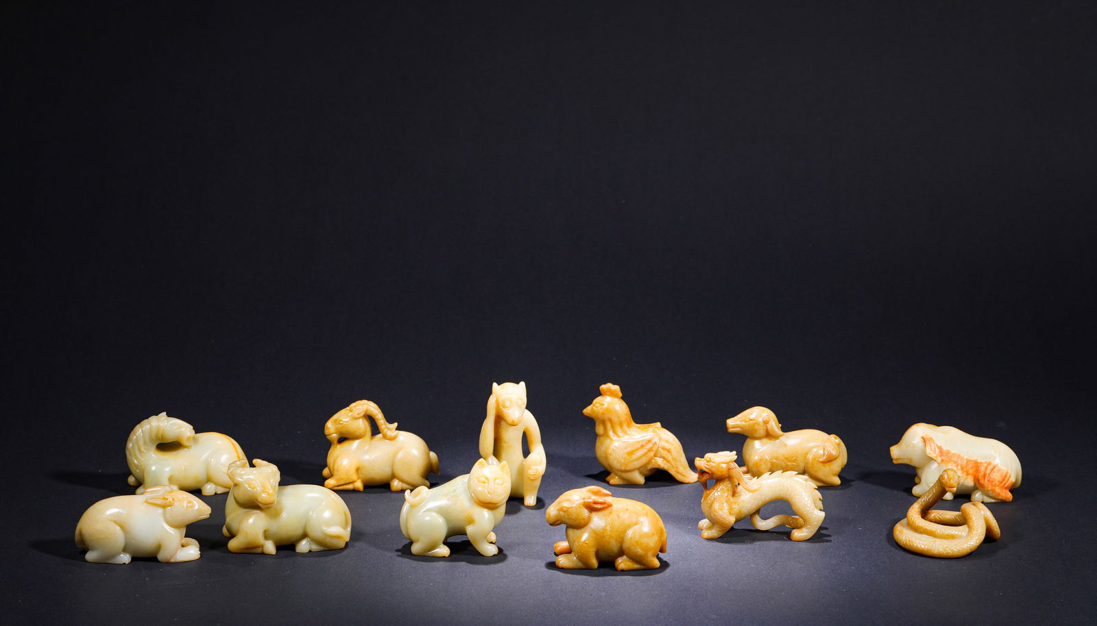 QING DYNASTY YELLOW JADE ZODIAC ORNAMENTS: H:4.5cmW:8cmWeight:1820g This is a set of Qing Dynasty yellow jade twelve zodiac animal figurines. Carved from Hetian yellow jade in the round, it depicts all twelve zodiac animals with vivid and