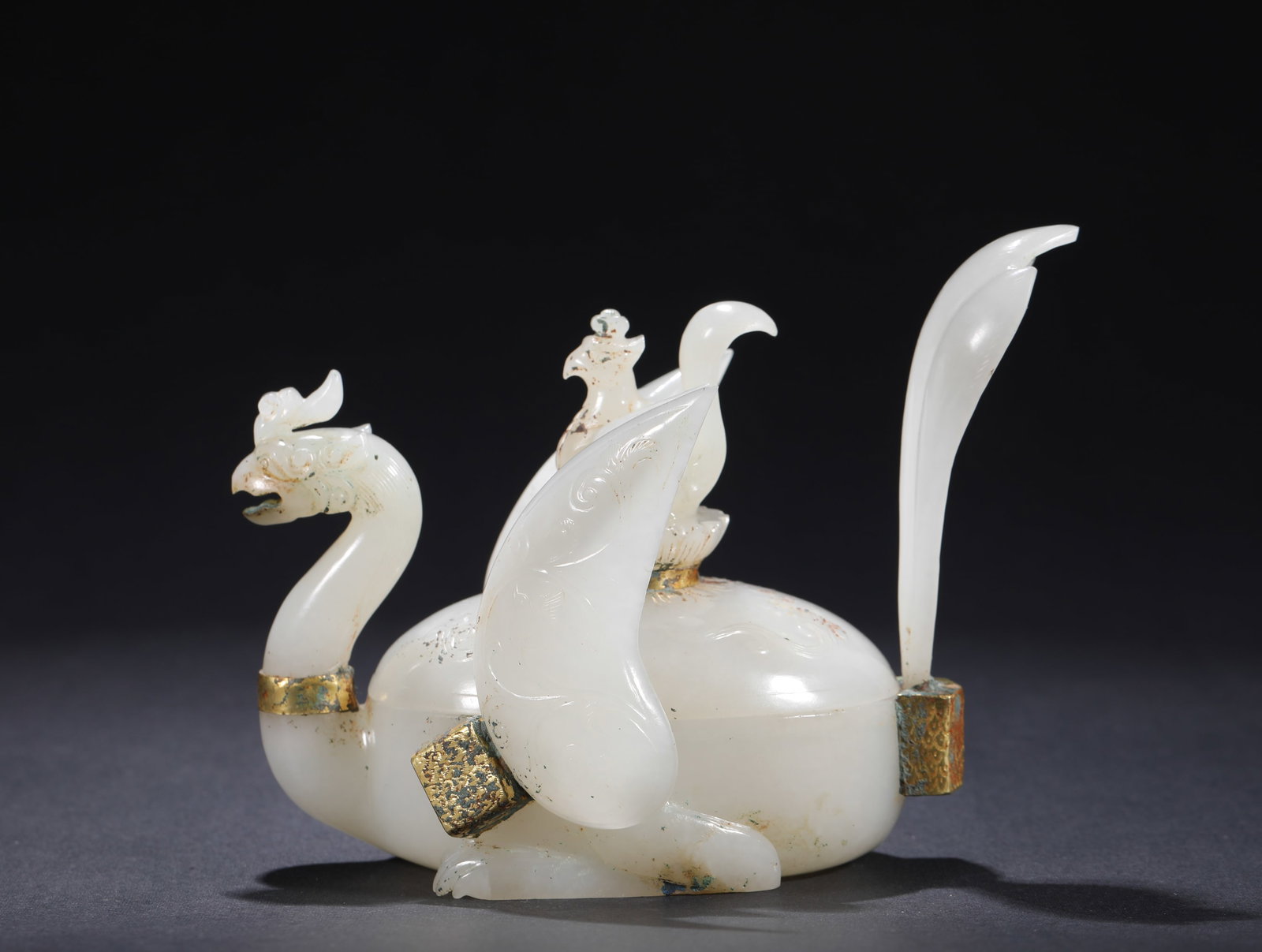 QING DYNASTY WHITE JADE ENCLOSING GOLDEN PHOENIX-SHAPED LID BOX: H:9.5cmW:12cmWeight:240g This is a Qing Dynasty white jade and gold-gilded phoenix-shaped lidded box. Carved from Hetian white jade, it is entirely shaped as a phoenix in the round, with the phoenix