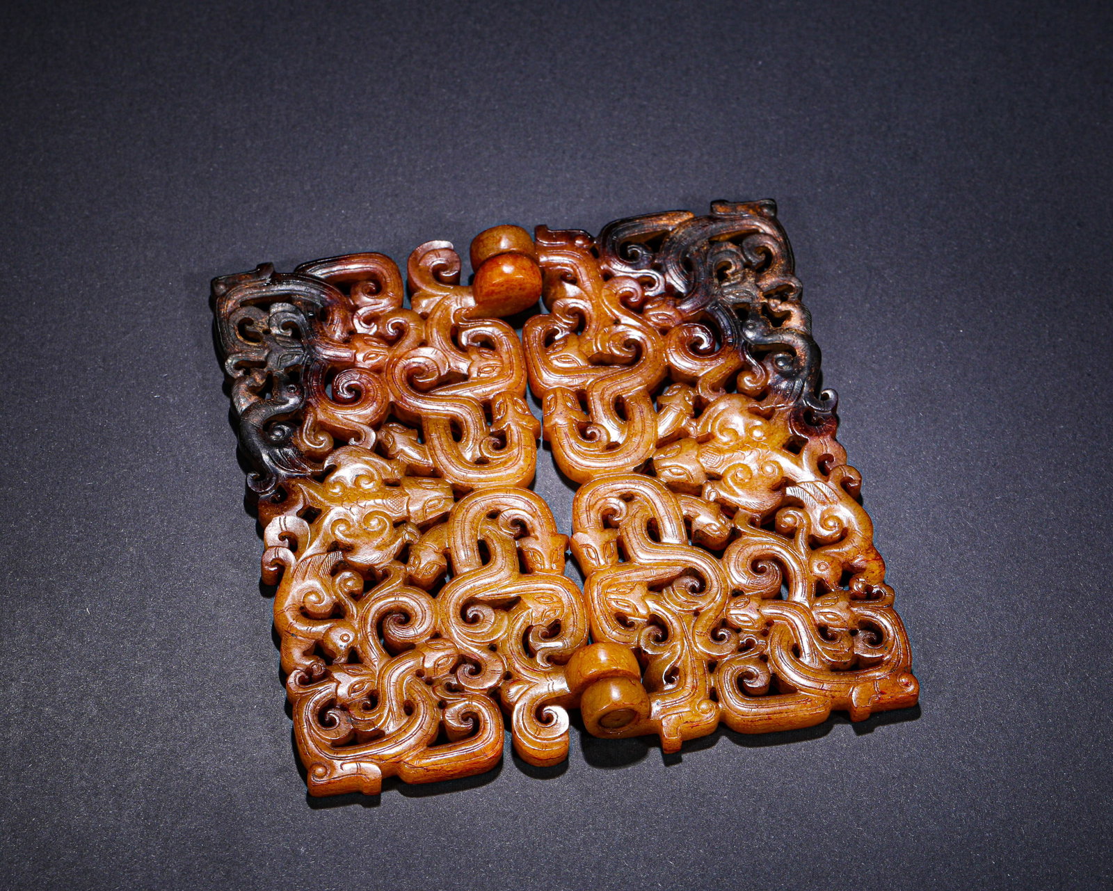 HAN DYNASTY THROUGH-CARVED CHON-DRAGON PATTERN DOUBLE LINKED JADE BELT BUCKLE: H:12.3cmW:11.8cmWeight:210g This is a double-linked jade belt hook carved with openwork chi-dragon patterns and natural color inclusions. Crafted from jade with deep and light brown inclusions, it