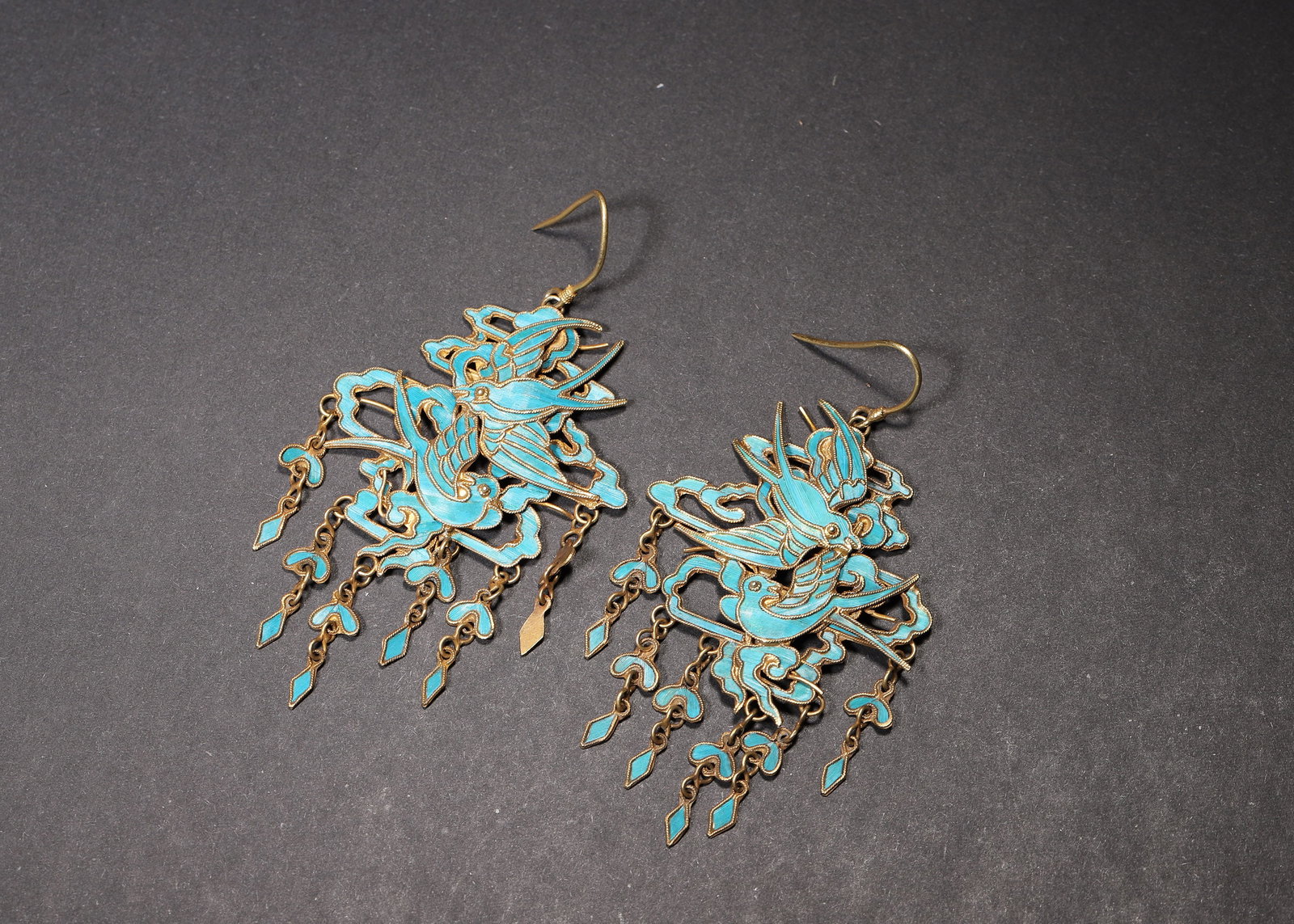 A FINE PAIR OF QING DYNASTY GILT-SILVER KINGFISHER FEATHER SWALLOW TASSEL EARRINGS: 2.76in x 1.57in (7.0cm x 4.0cm), 0.029lb (13.0g)This pair of Qing Dynasty earrings is crafted from gilt-silver with vibrant kingfisher feather swallow-and-cloud motifs, adorned with delicate gilt tass
