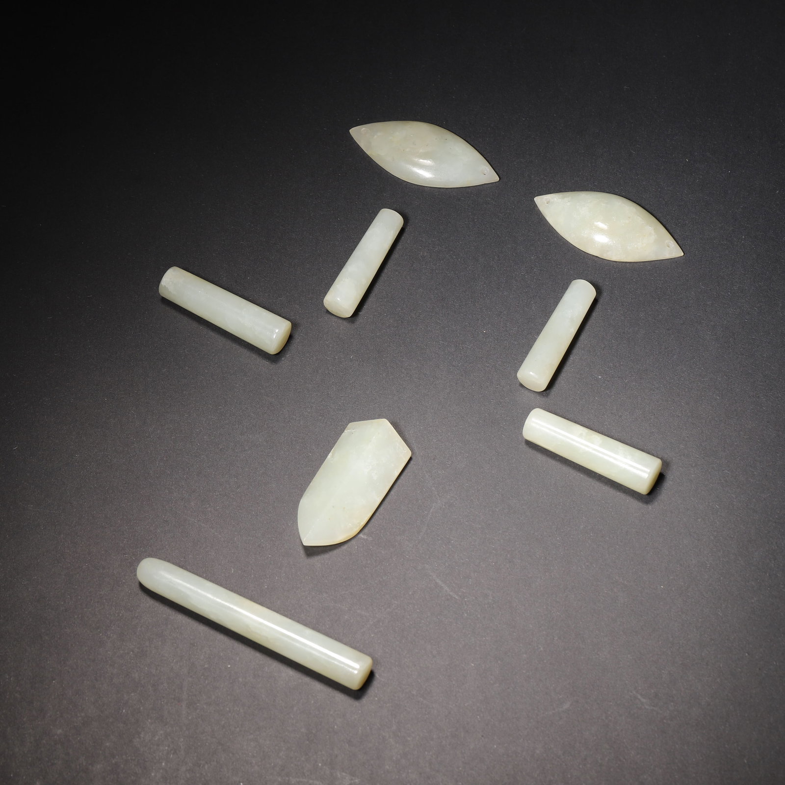 A SET OF EIGHT HETIAN PALE GREENISH WHITE JADE NINE-ORIFICE FUNERAL JADES, HAN DYNASTY: L: 7cm (2.76in) Weight: 78.37g (0.17lb)This rare set of 8 Hetian pale greenish white jade nine-orifice funeral jades from the Han Dynasty, crafted with the iconic "Han Eight Cuts" technique, is a top-