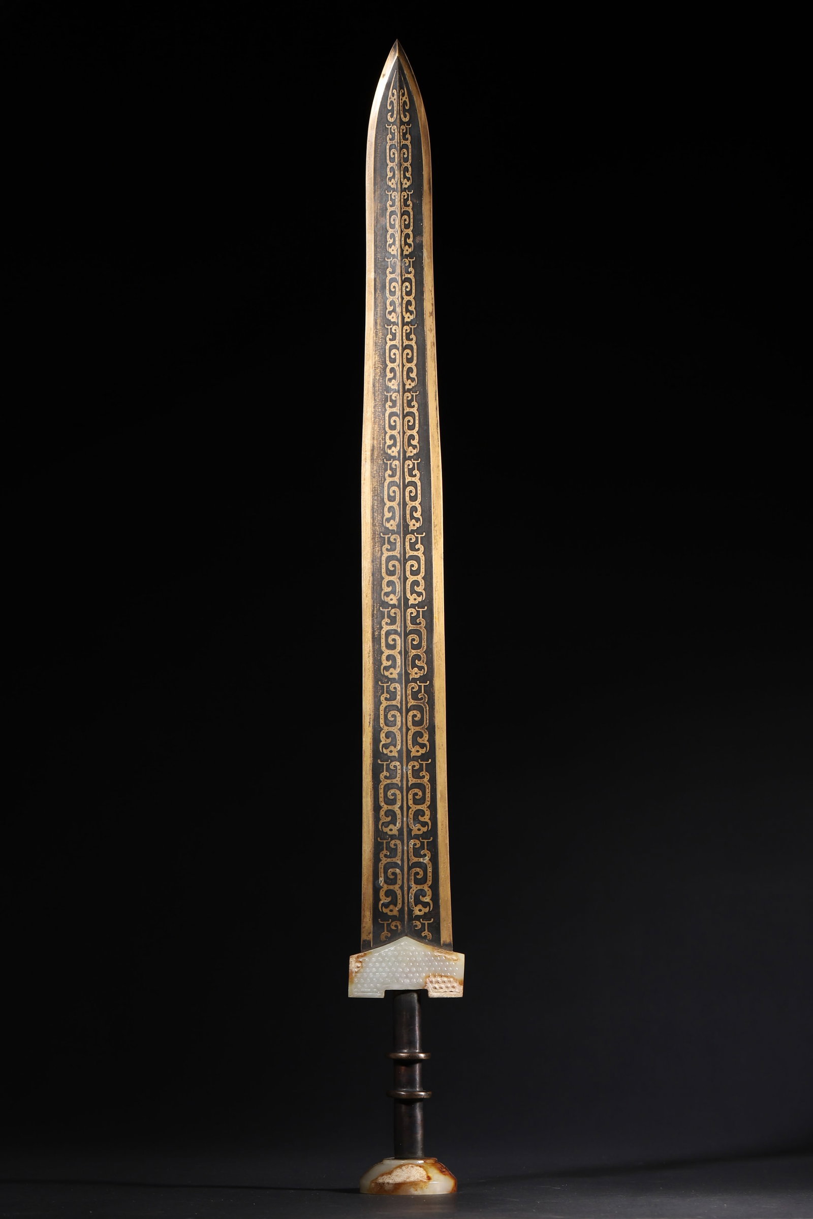 A FINE WARRING STATES TO HAN DYNASTY GOLD-INLAID BRONZE ORNAMENT WITH JADE GUARD AND POMMEL: 25.2in x 2.36in (64.0cm x 6.0cm), 2.227lb (1010.0g)This Warring States to Han Dynasty bronze ornament features intricate gold-inlaid cloud patterns, paired with a jade guard and pommel with original e