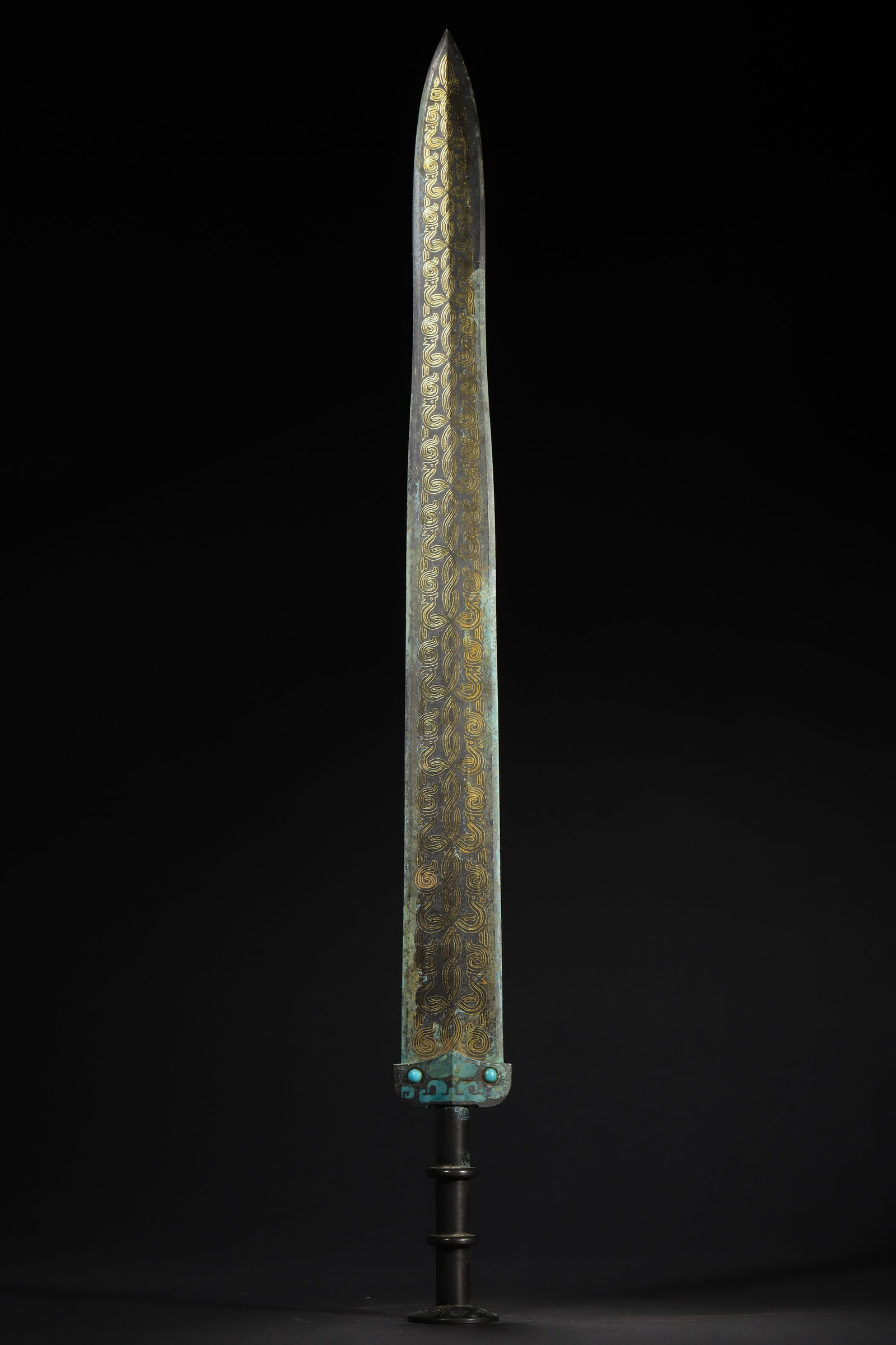 WARRING STATES TO HAN DYNASTY BRONZE ORNAMENT WITH GOLD INLAID CLOUD PATTERNS AND TURQUOISE INLAY: 24.02in x 2.2in (61.0cm x 5.6cm), 2.121lb (962.0g)A fine Warring States to Han Dynasty bronze ornament with gold-inlaid scrolling cloud patterns, turquoise inlay, and concentric pommel. Exemplifying a