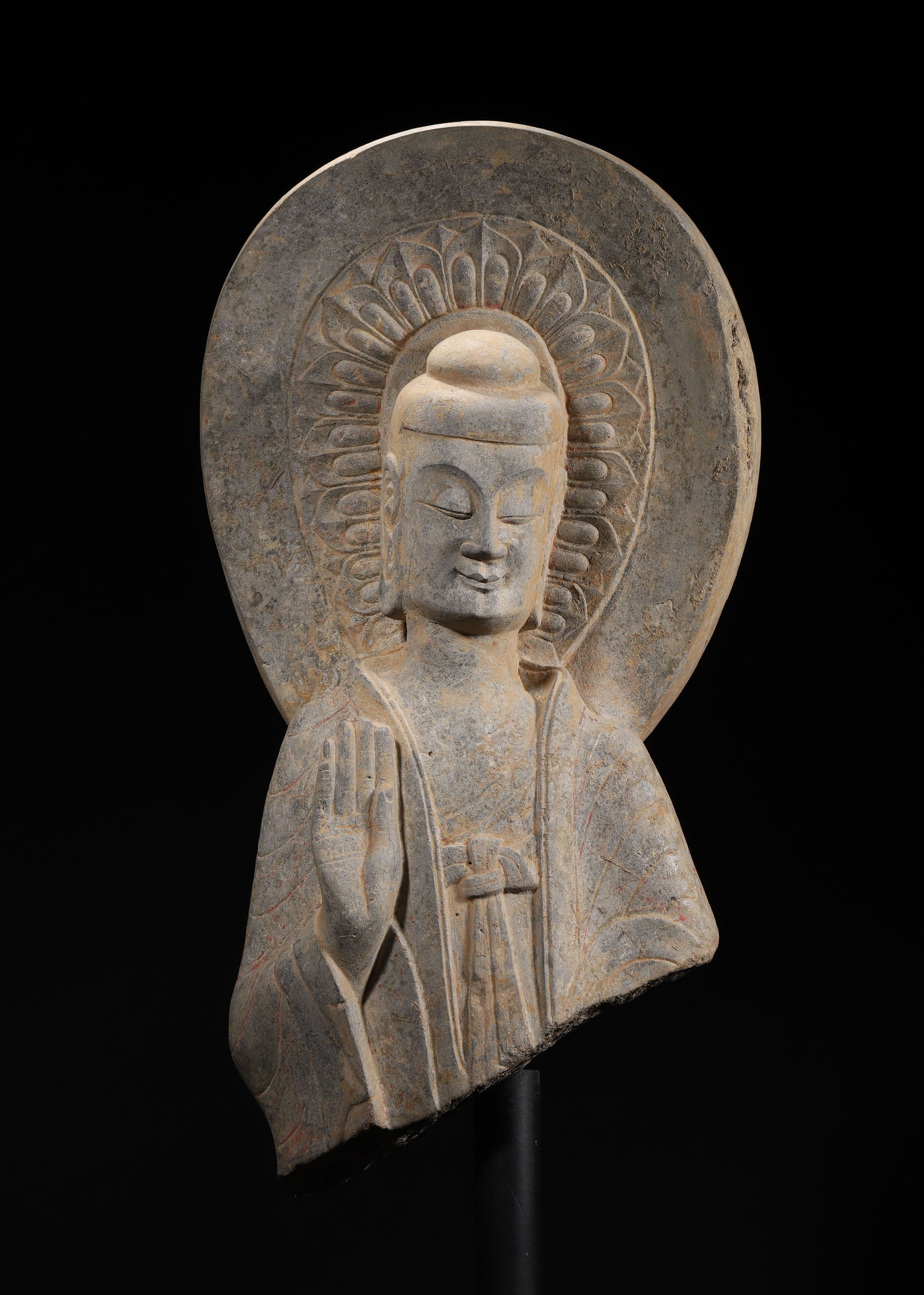 A SUI/TANG DYNASTY GREY STONE CARVED BUST OF BUDDHA: 7.87" x 4.33" x 16.93" x 5.12" (20cm x 11cm x 43cm x 13cm)This Sui/Tang Dynasty grey stone Buddha bust features serene expression, abhaya mudra, lotus-patterned mandorla, and residual cinnabar pigment