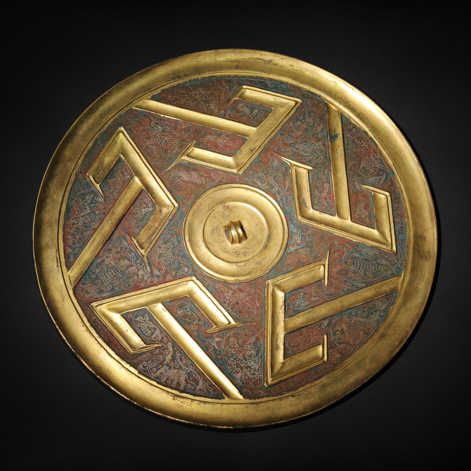 WARRING STATES PERIOD GILT BRONZE MIRROR WITH FIVE "MOUNTAIN" PATTERNS AND INLAID COLOR DECORATION: 13.19in (33.5cm), 5.906lb (2679.0g)A Warring States gilt bronze mirror featuring five raised "mountain" patterns, with intricate inlaid cloud and beast motifs on the ground. It represents the peak of