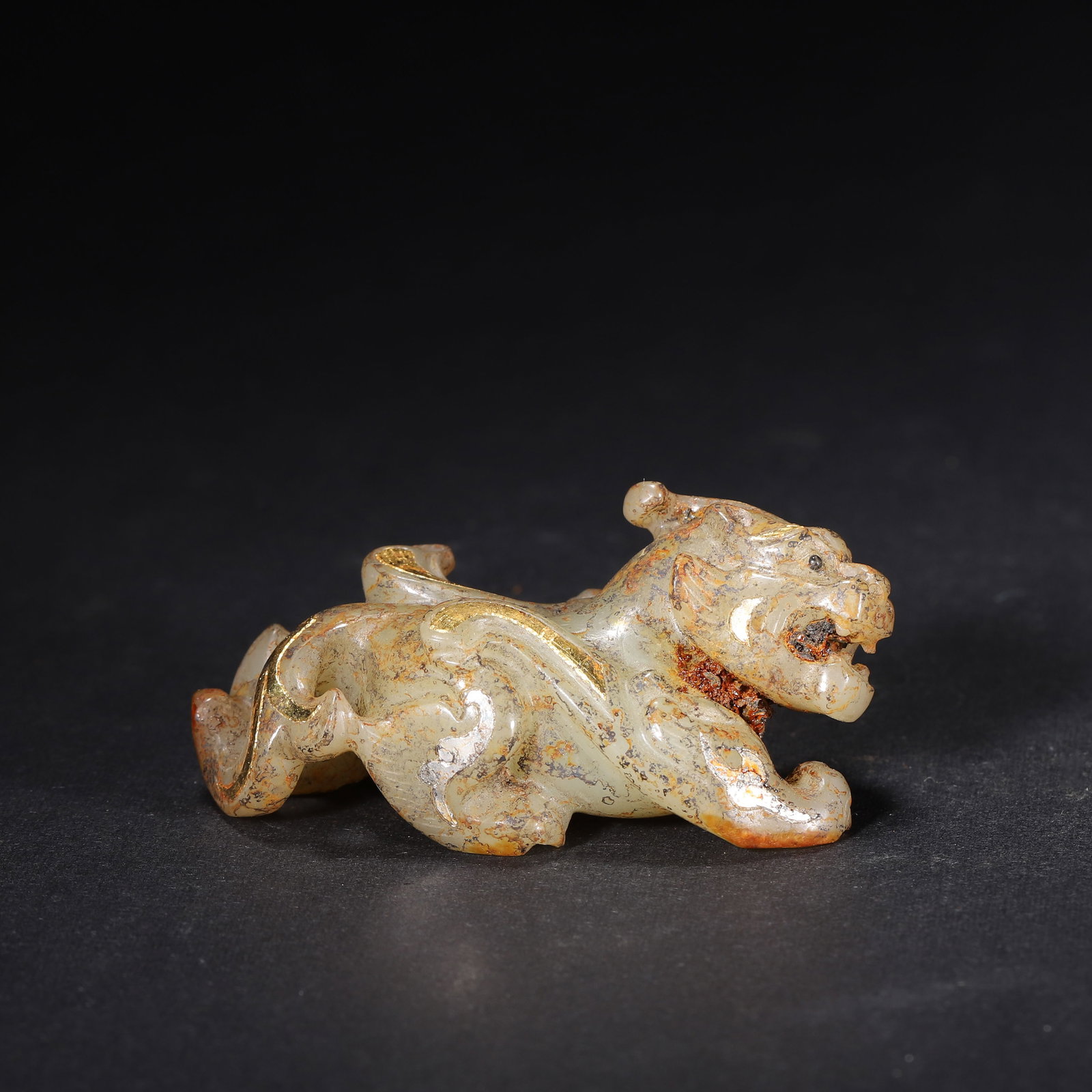 HAN DYNASTY GOLD & SILVER INLAID JADE PIXIU (MYTHICAL BEAST) ORNAMENT: 2.2" x 1.1" x 1.1" (5.6cm x 2.8cm x 2.8cm) | 0.088lb (40g)This powerful Han Dynasty jade Pixiu, inlaid with gold and silver scroll patterns, crouches dynamically. Its aged earth patina and robust carv
