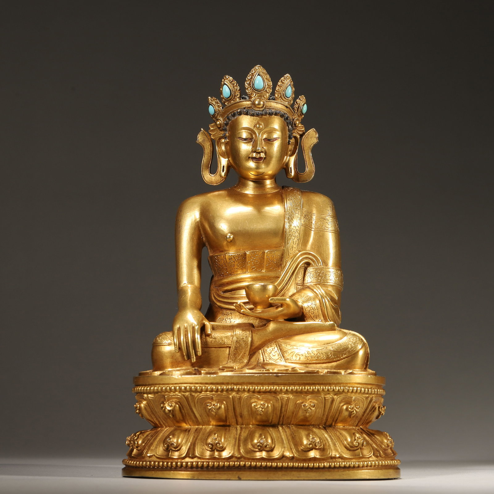 A GILT-BRONZE CROWNED SAKYAMUNI BUDDHA WITH TURQUOISE, QING DYNASTY: L: 12cm (4.72in) W: 9cm (3.54in) H: 19cm (7.48in) Weight: 1382g (3.05lb)A superb Qing Dynasty gilt-bronze crowned Sakyamuni Buddha, turquoise-inlaid, lotus pedestal, exquisite craftsmanship, rich gild