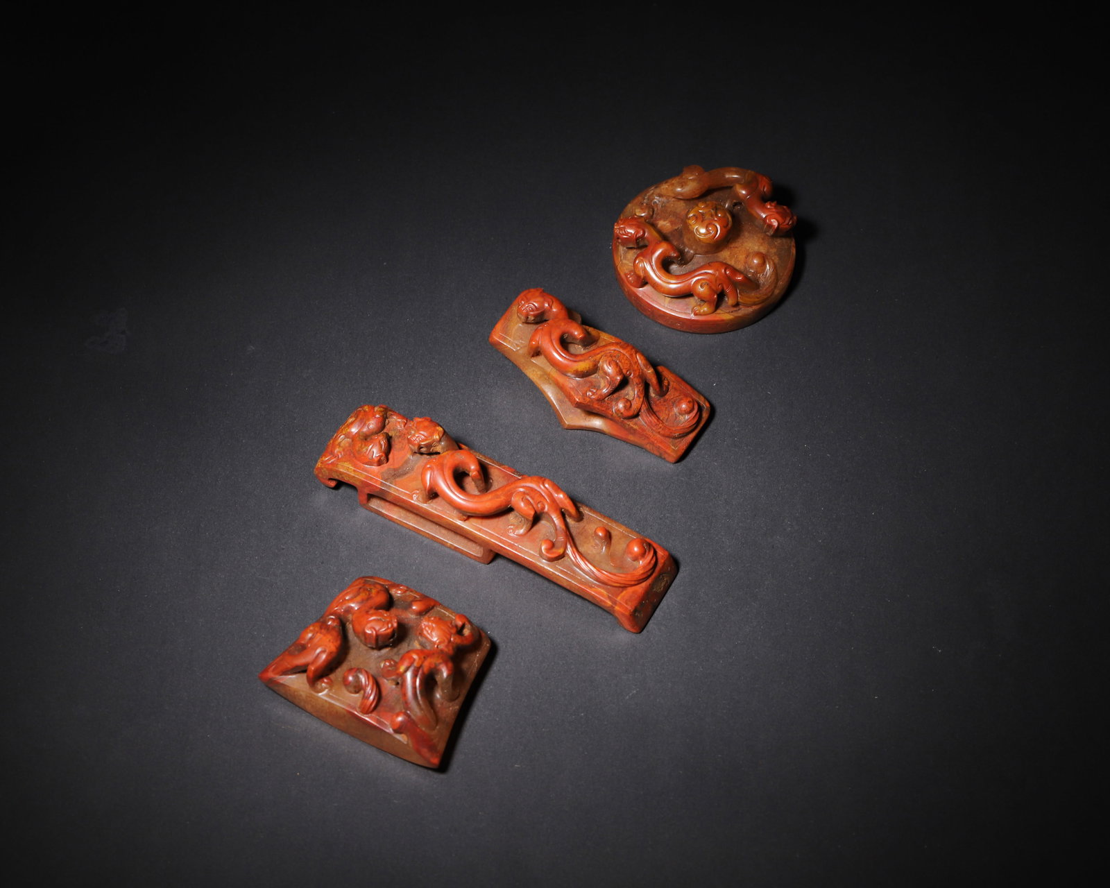 A SET OF FOUR RED-INFILTRATED HETIAN JADE SWORD ORNAMENTS WITH CHI-DRAGON PATTERNS, HAN DYNASTY (1 of 10)