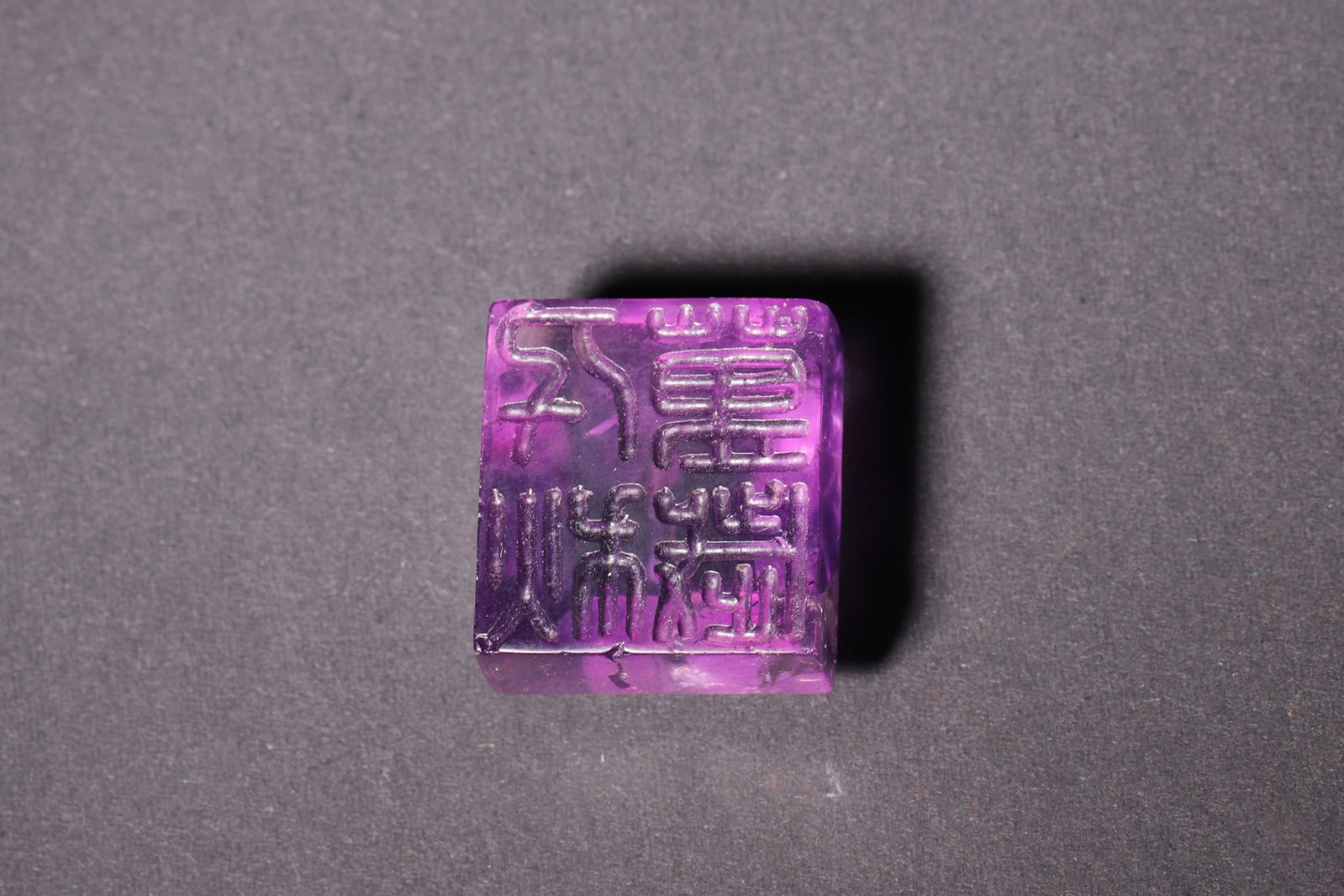 A Han Dynasty Amethyst Seal with Dou-Shaped Knob: Length 2.6cm (1.02in), Width 2.4cm (0.94in), Weight 22.0g (0.05lb)A Han Dynasty amethyst seal with a dou-shaped knob, carved with seal script characters. The transparent and rich purple amethyst refle