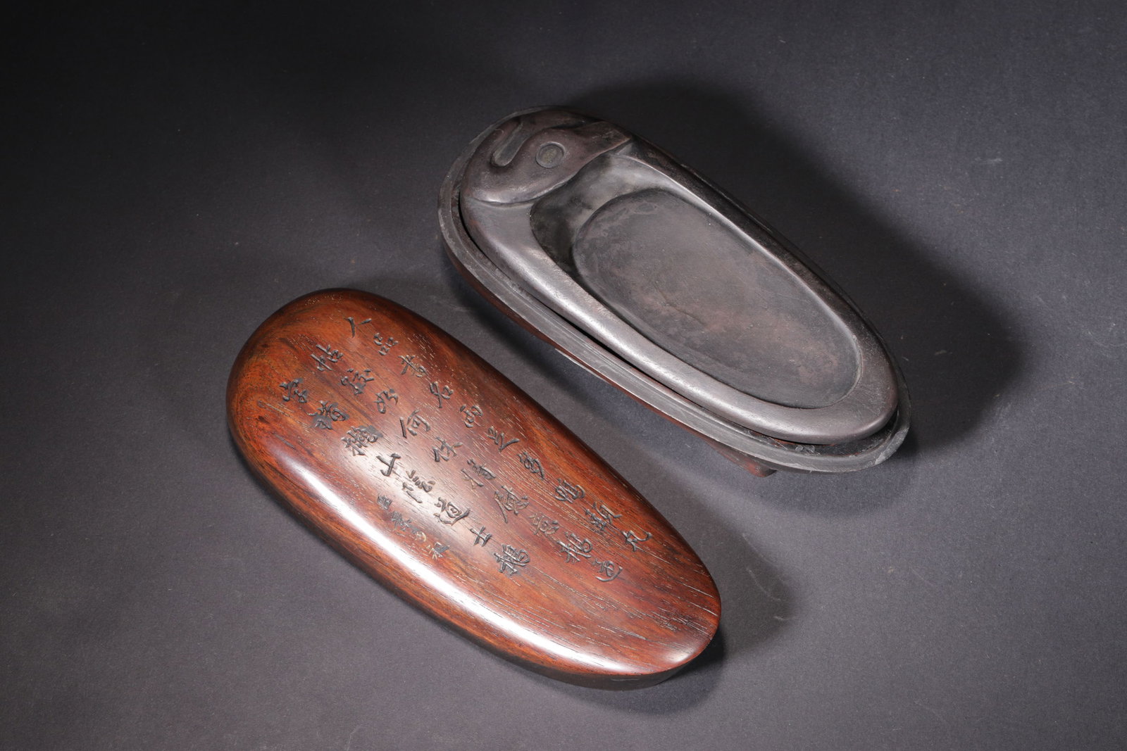 A Duck-shaped Duan Inkstone with Poem Inscription (Qing Dynasty): Length 14.0cm (5.51in), Width 5.5cm (2.17in), Weight 471.0g (1.04lb)This Qing Dynasty inkstone, made of fine Duan stone in a duck shape, comes with a red sandalwood box carved with poems. It is a clas