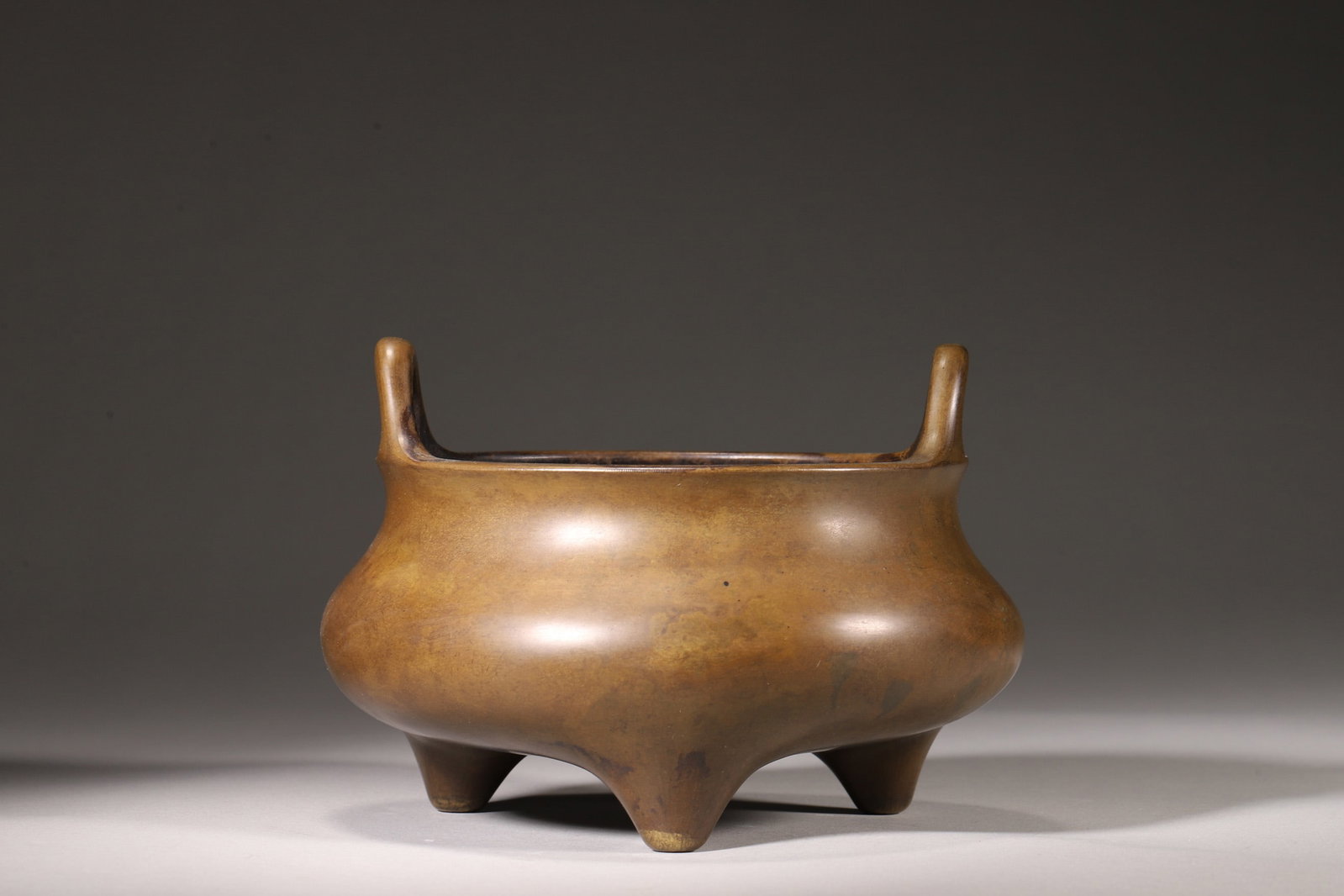 A Bronze Three-Foot Incense Burner with Bridge Handles, "Yutang Qingwan?? Mark, Qing Dynasty: Diameter 16.0cm (6.3in), Height 11.0cm (4.33in), Weight 1364.0g (3.01lb)A bronze three-foot incense burner with bridge handles, bearing the "Yutang Qingwan" mark, dating to the Qing Dynasty. Cast from