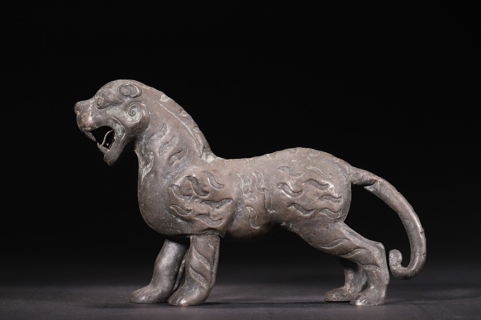 A Silver Tiger-Form Auspicious Beast Ornament, Tang Dynasty: Length 16.0cm (6.3in), Width 4.0cm (1.57in), Height 11.0cm (4.33in), Weight 275.0g (0.61lb)A silver tiger-form auspicious beast ornament of the Tang Dynasty. Cast in silver with a powerful, dynamic po