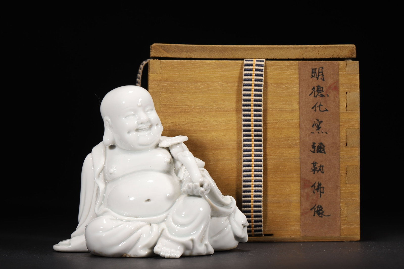 A Dehua Kiln White Glazed Maitreya Buddha Statue Holding Ruyi, Ming Dynasty: 10.0 x 7.0 x 8.5 cm (L x W x H = 3.94 x 2.76 x 3.35 in)This is a Ming Dynasty Dehua Kiln white glazed Maitreya Buddha statue holding a ruyi. With firm body, ivory-like lustrous glaze, a joyful and