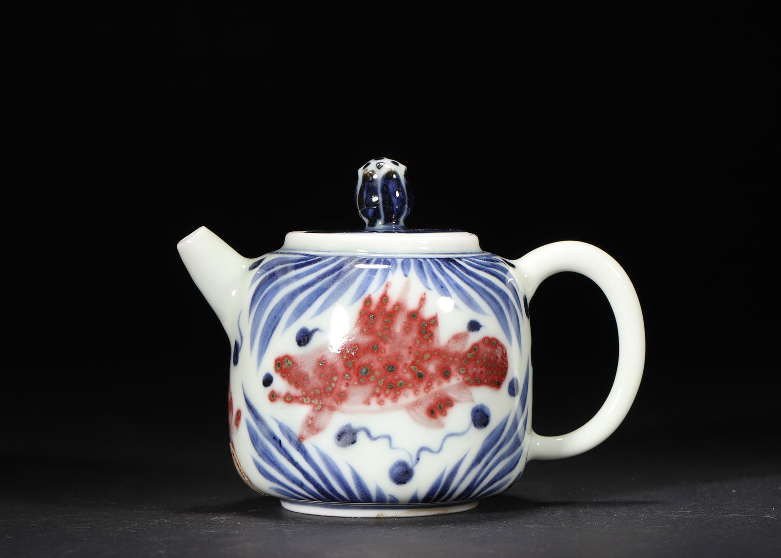 A Ming Dynasty Blue and White with Underglaze Red Fish and Algae Pattern Teapot, Xuande Mark: 12.0 x 7.5 x 8.5 cm (L x W x H = 4.72 x 2.95 x 3.35 in)This Ming Dynasty Xuande-marked teapot features a plump, well-proportioned form with a short spout, curved handle, and an elegant