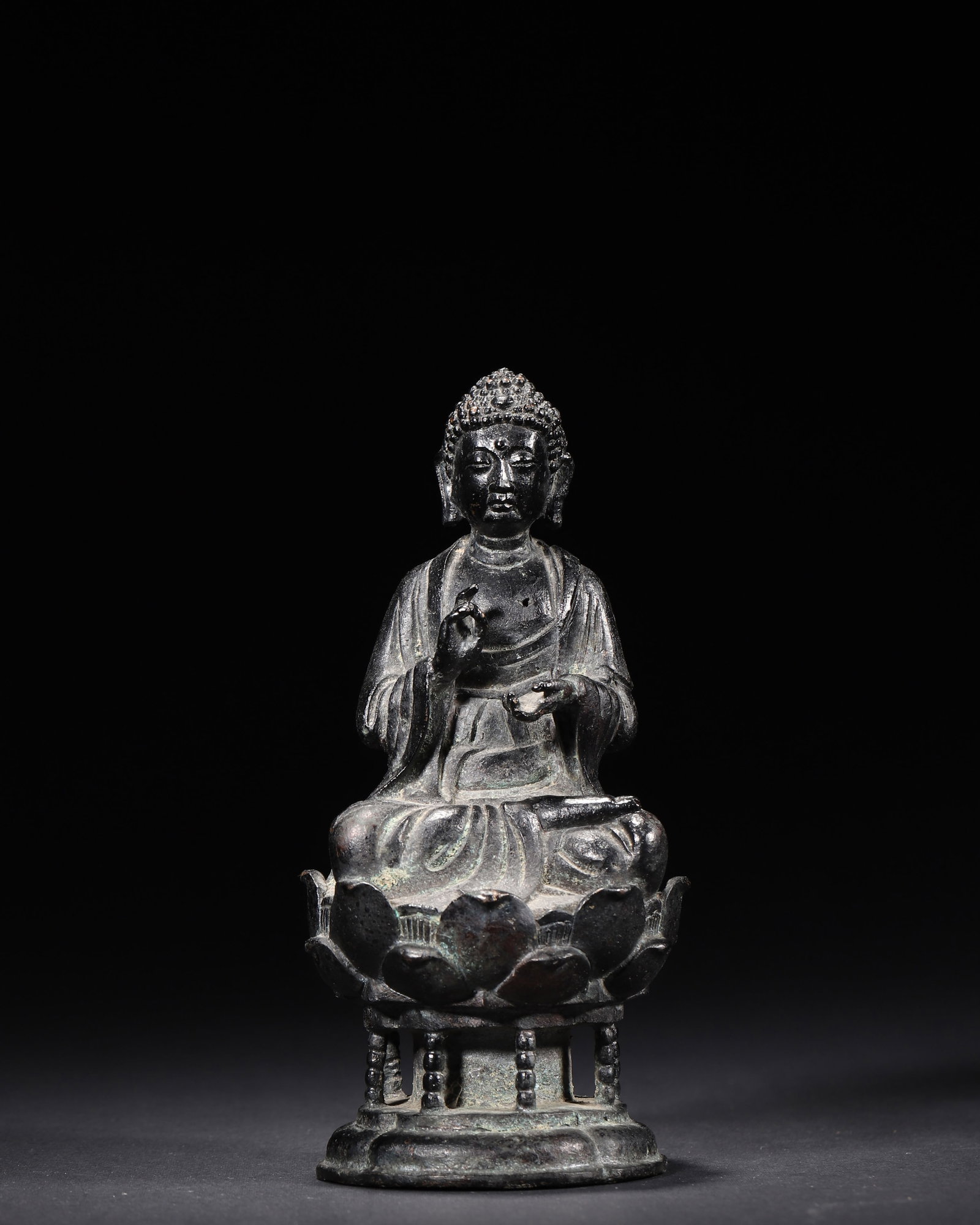 A Bronze Seated Statue of Sakyamuni Buddha, Ming Dynasty: 7.0 x 7.0 x 16.0 cm (2.76 x 2.76 x 6.3 in), WT 929.0 g (2.05 lb)A bronze seated statue of Sakyamuni Buddha, Ming Dynasty. The Buddha sits in lotus position on a lotus throne with a railing-style base.