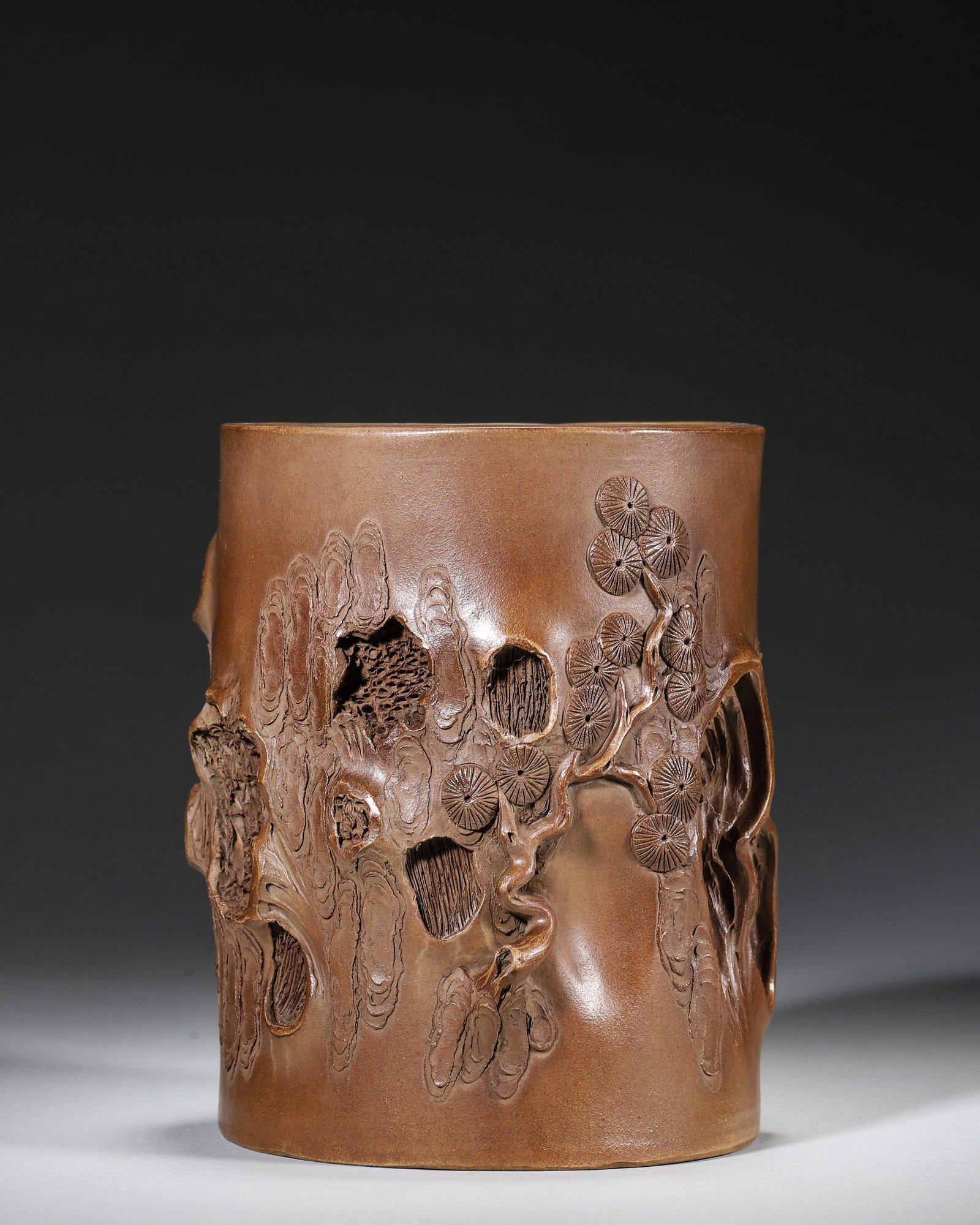 Qing Dynasty - Zisha Brush Pot with Pine Stump Motif, Attributed to Chen Mingyuan: D 12.0 cm (D 4.72 in)Crafted from purple sand, this brush pot imitates a pine stump in its entirety. The bark texture is exquisitely carved, with vivid knots and pine needles. Poems are inscribed on